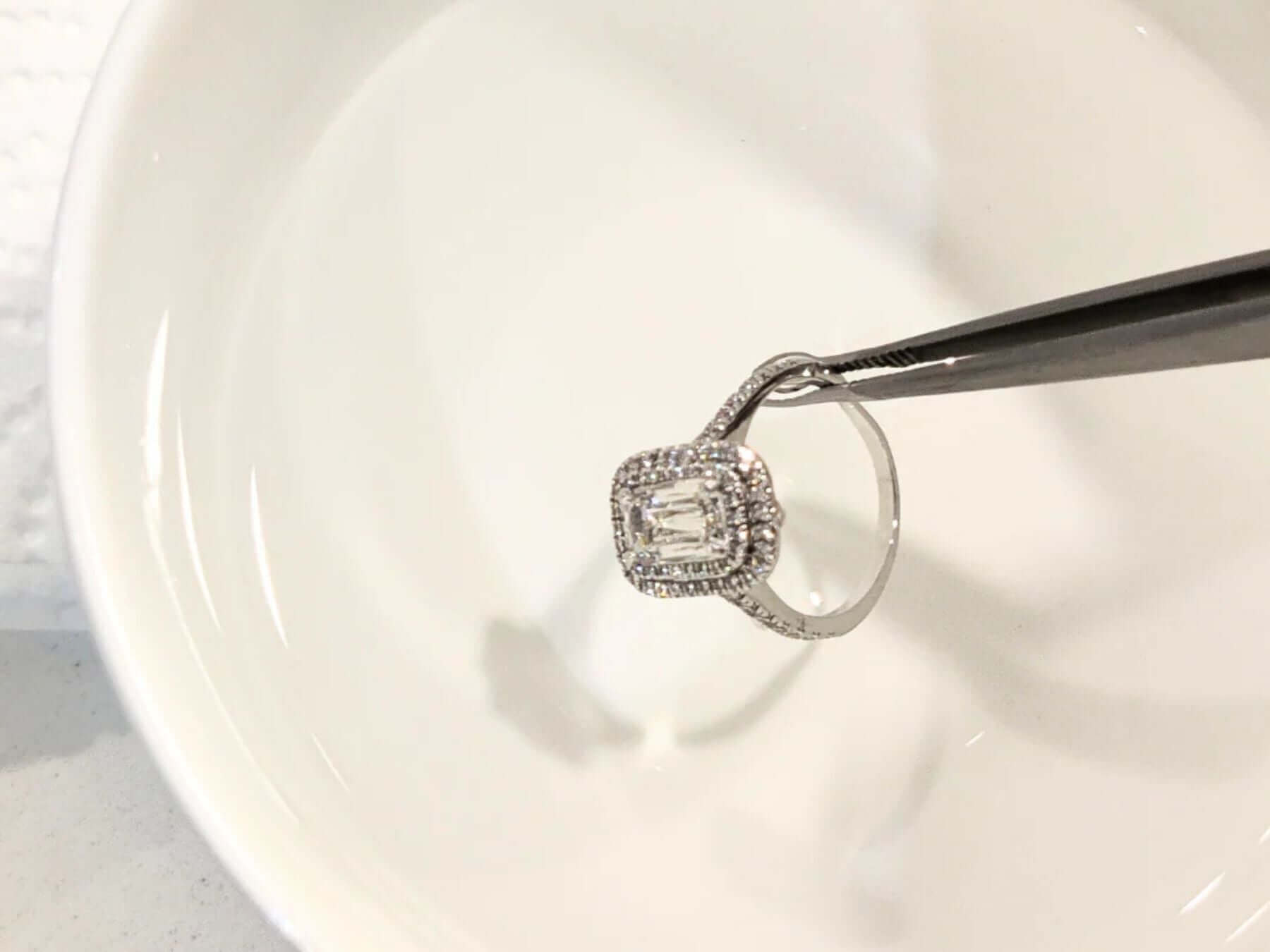 Cleaning diamond jewellery in a bowl of water with tweezers to keep it sparkling and beautiful.