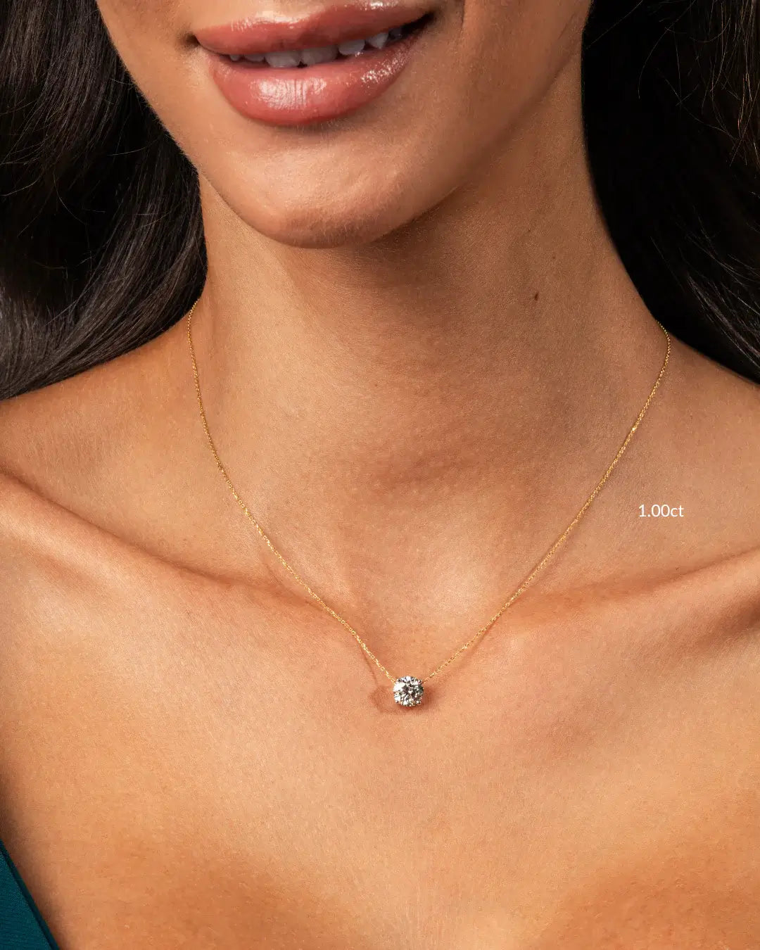 Elegant model showcasing a floating diamond necklace with a round brilliant cut diamond on a fine gold chain.