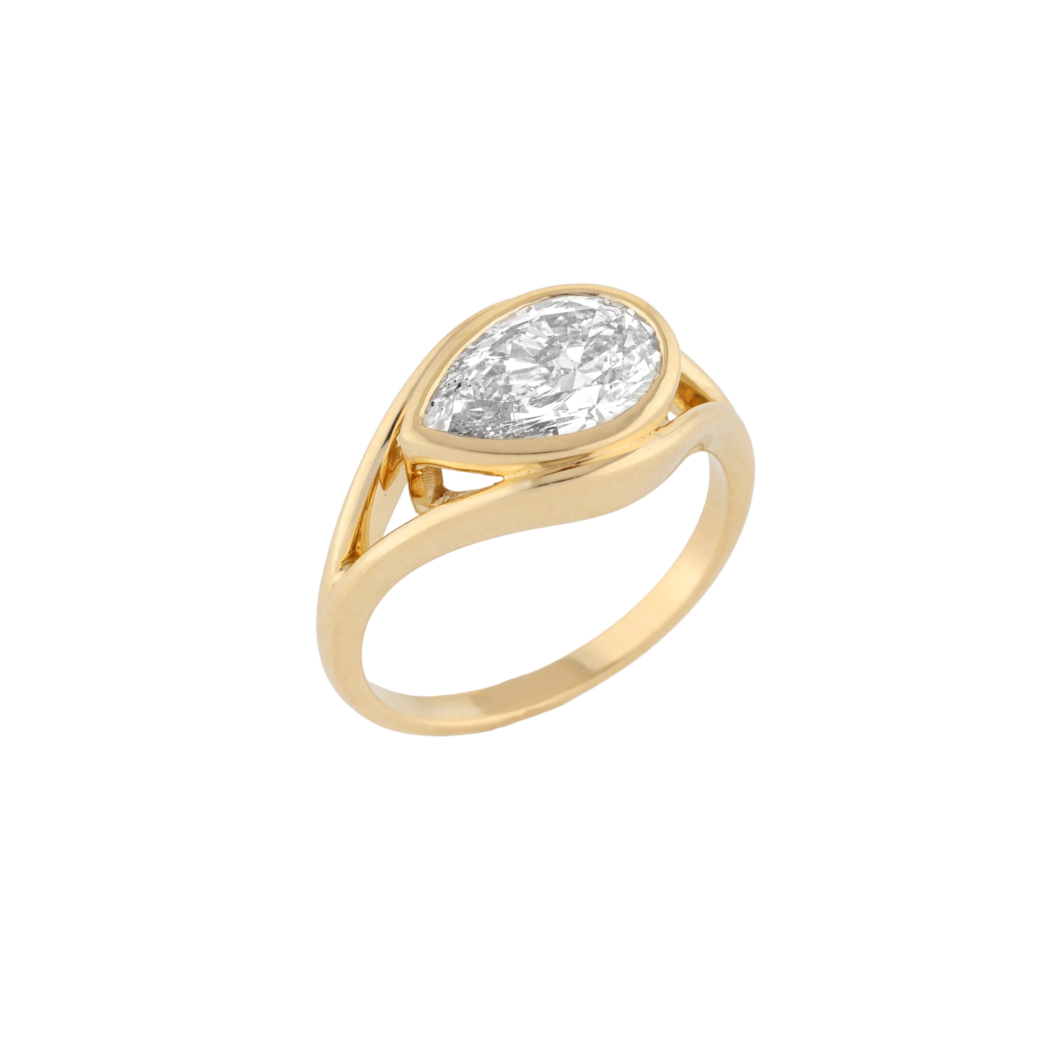 A yellow gold ring featuring a large, pear cut diamond in a prong setting, shown on a clean white background.