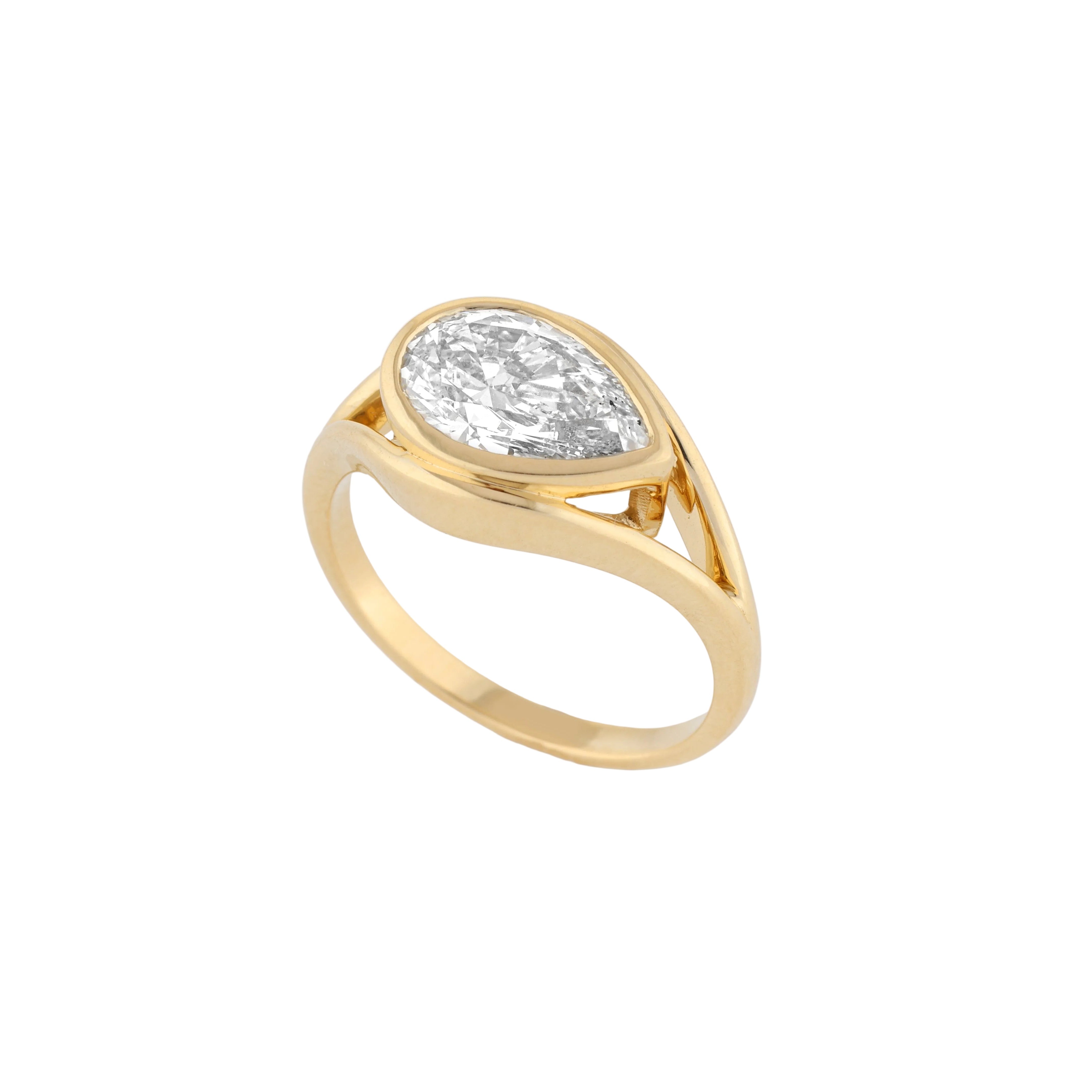 A yellow gold ring featuring a large, pear cut diamond in a prong setting, shown on a clean white background.