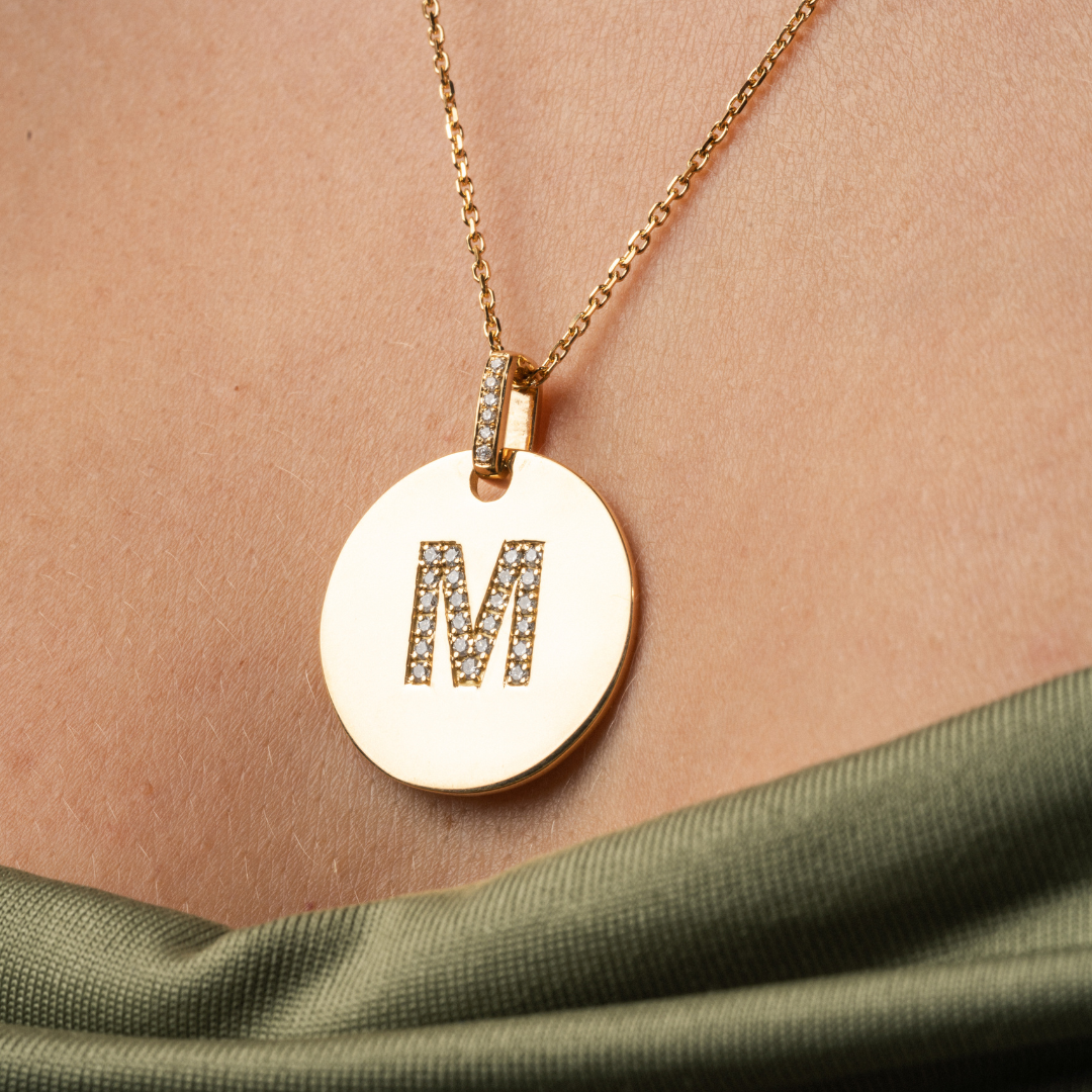 Love Letter Disk necklace featuring an M initial, set in 18ct gold with certified diamonds, elegantly displayed.