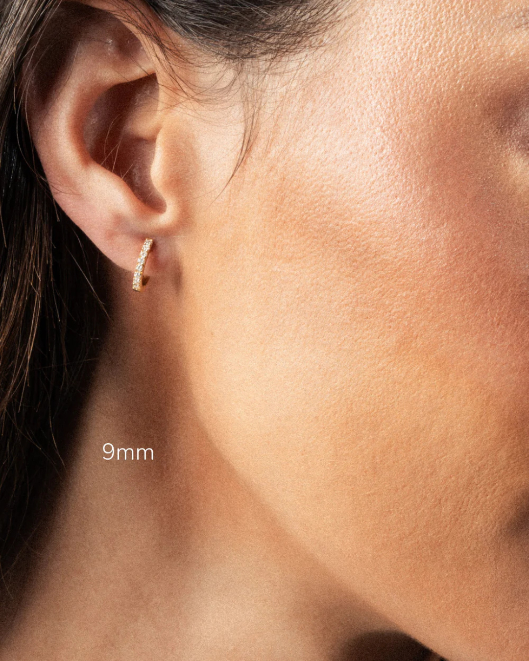 Close-up of an ear wearing a diamond hoop earring with '9mm'