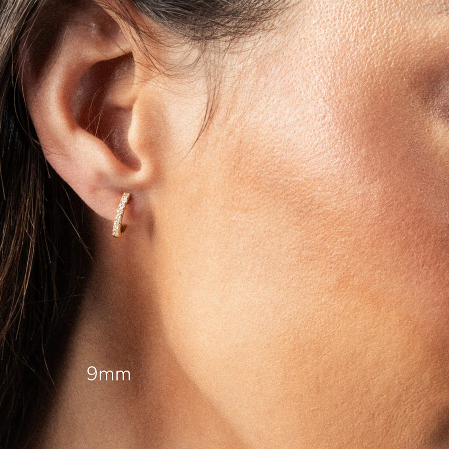 Close-up of an ear wearing a gold diamond hoop earring with '9mm' .