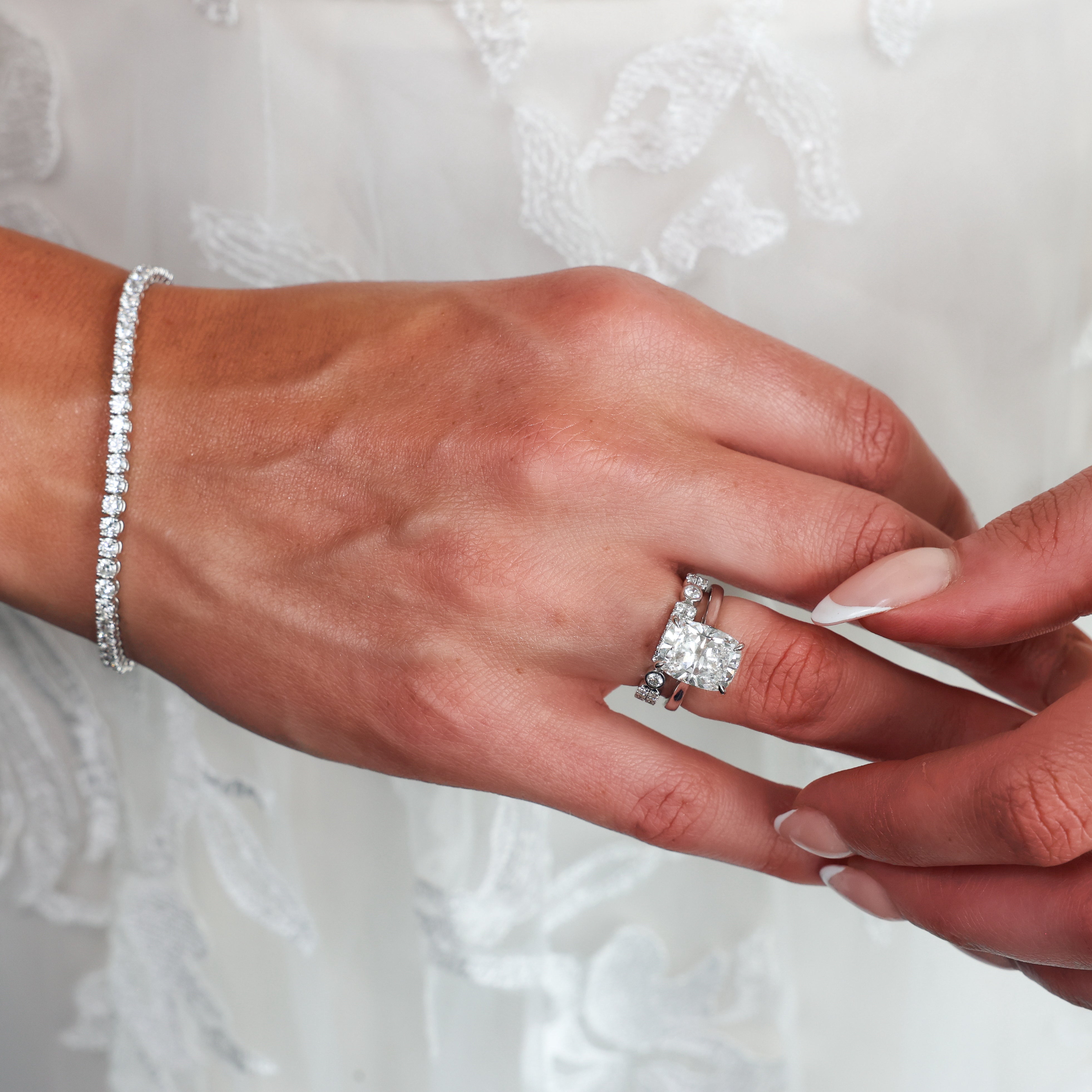 A close-up of a hand wearing a diamond ring with a diamond engagement ring, while another hand holds it.