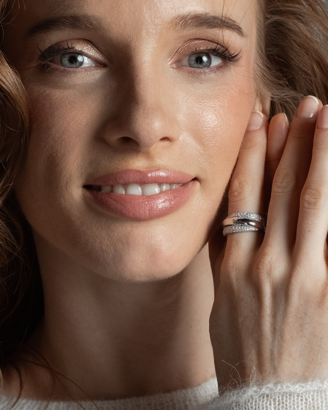 A woman showcasing The Aurora Ring, a gold and diamond ring with overlapping strands, highlighting the beauty of certified diamond rings.
