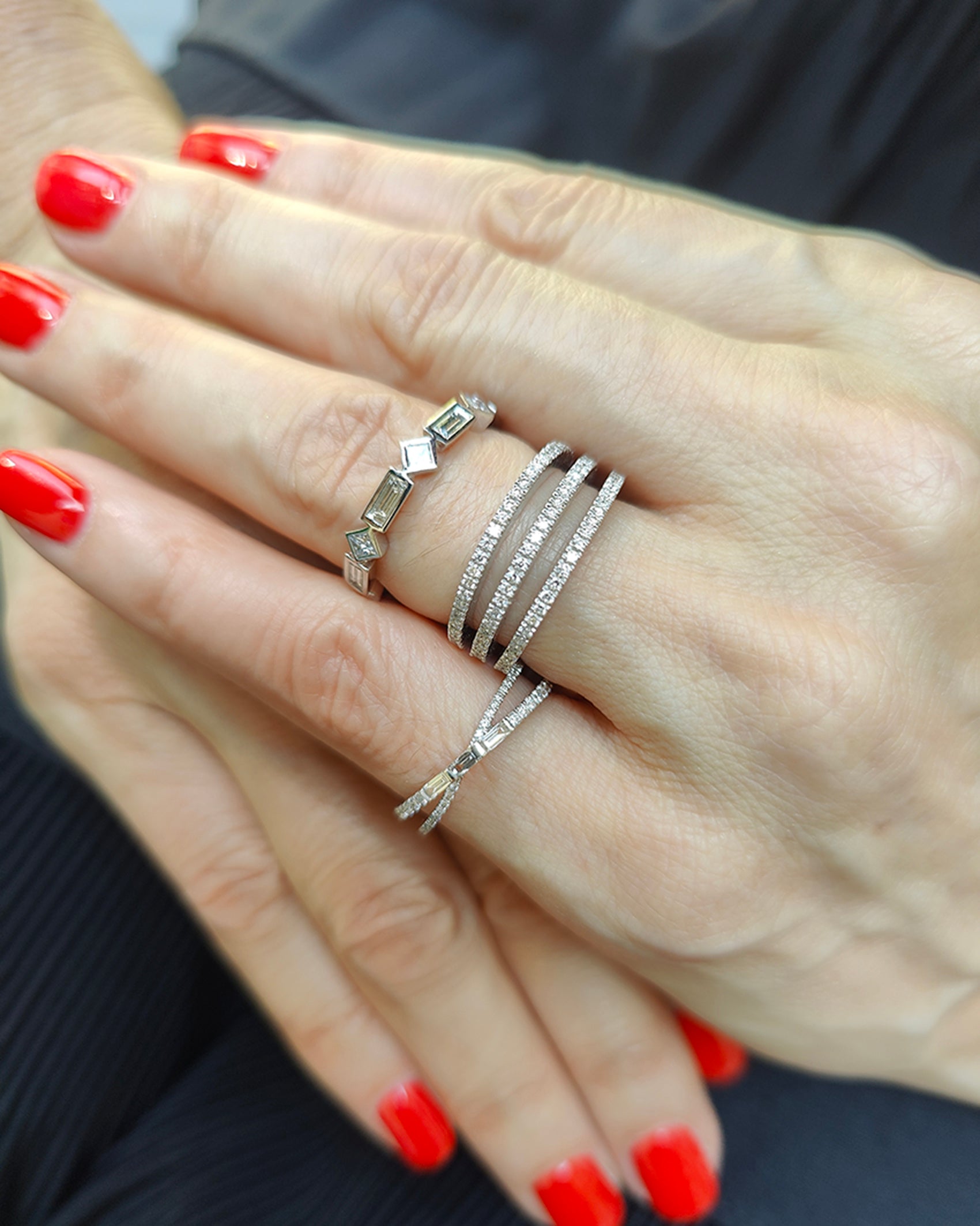 Diamond ring display featuring modern criss cross designs with baguette and round cut diamonds on elegantly manicured hands.