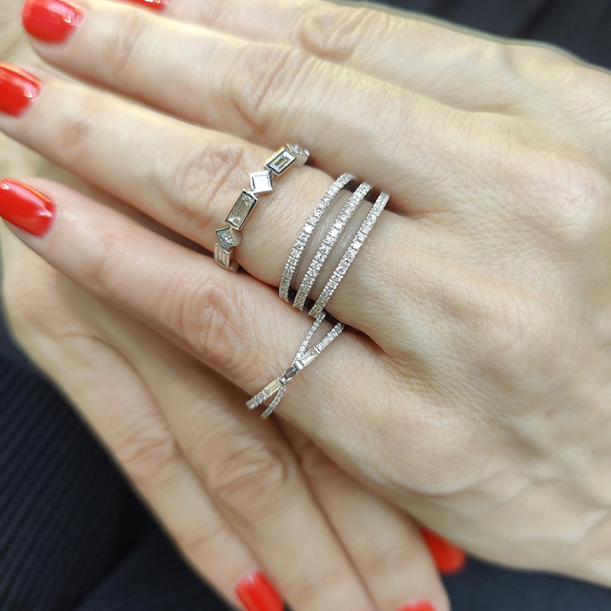 Diamond ring display featuring modern criss cross designs with baguette and round cut diamonds on elegantly manicured hands.