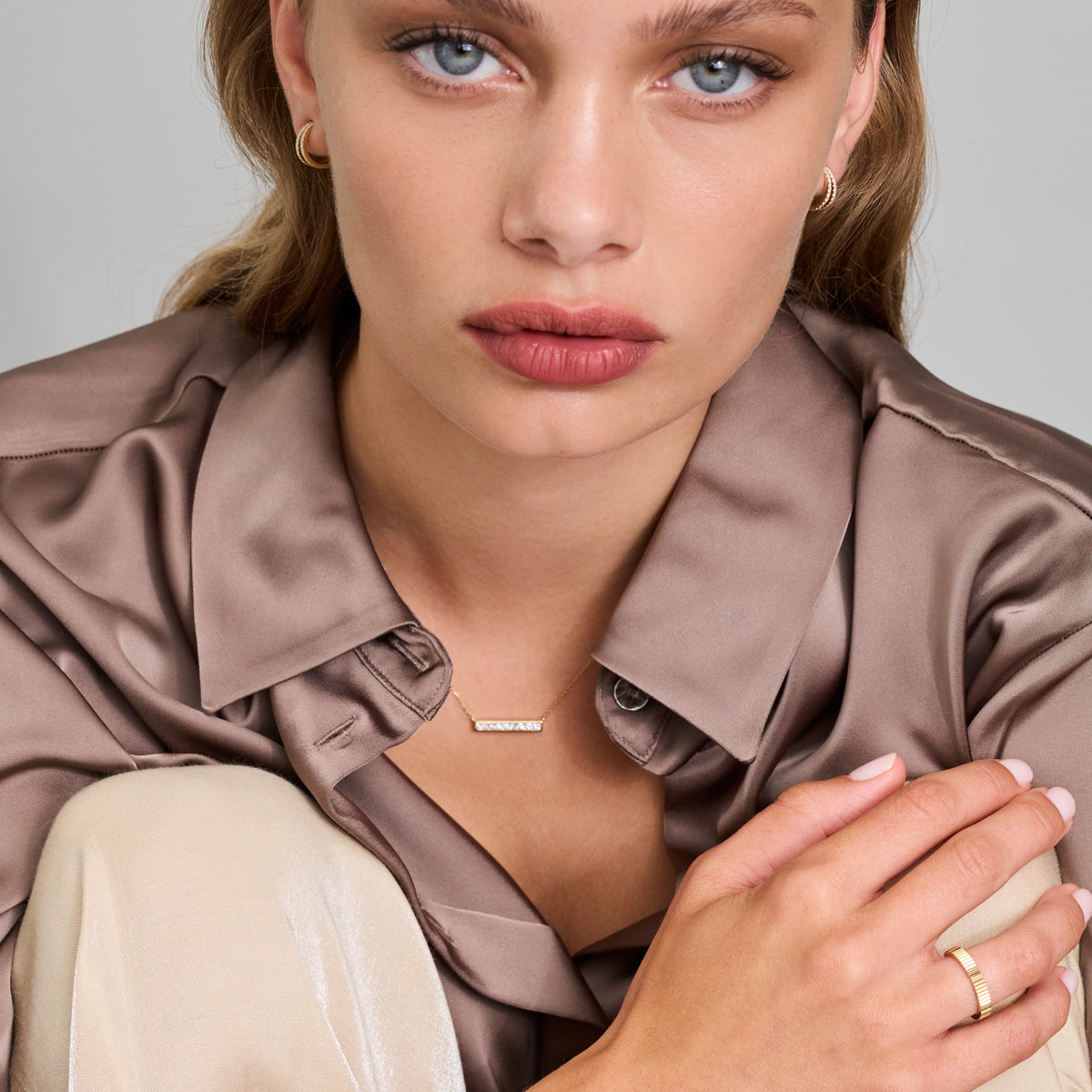 Model wearing a diamond bar necklace, showcasing modern elegance with a delicate gold chain and princess-cut diamonds.