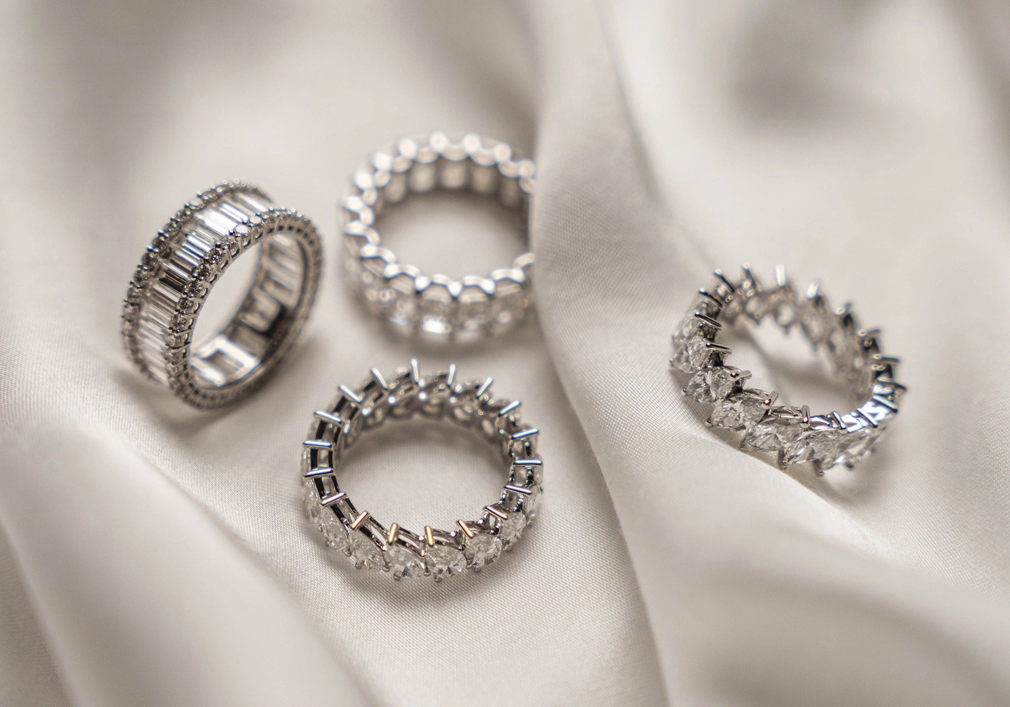 Custom made diamond rings, displayed on soft white fabric, showcasing brilliant cuts and settings