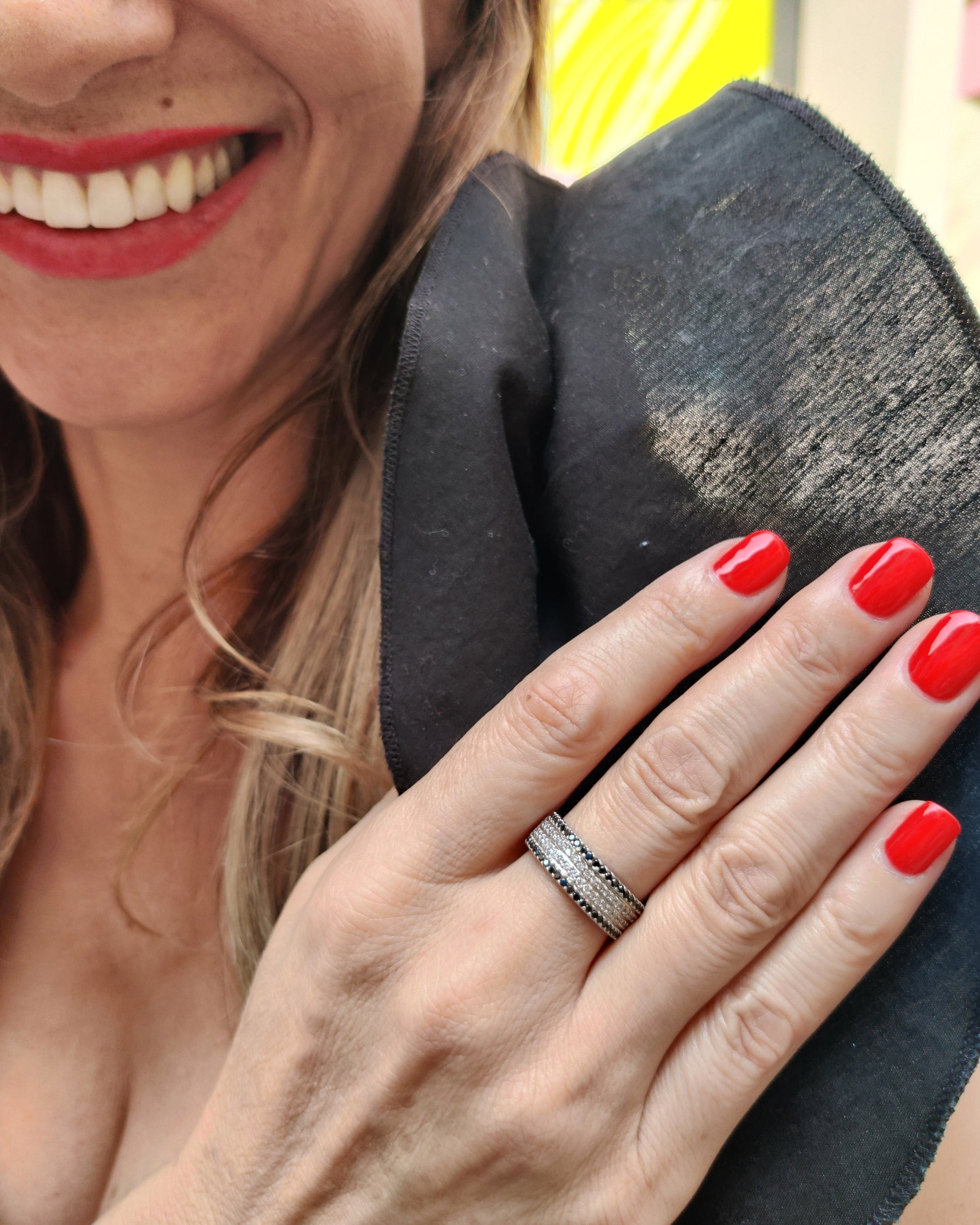 Woman showcasing a stunning black and white diamond ring on her finger with red nail polish.