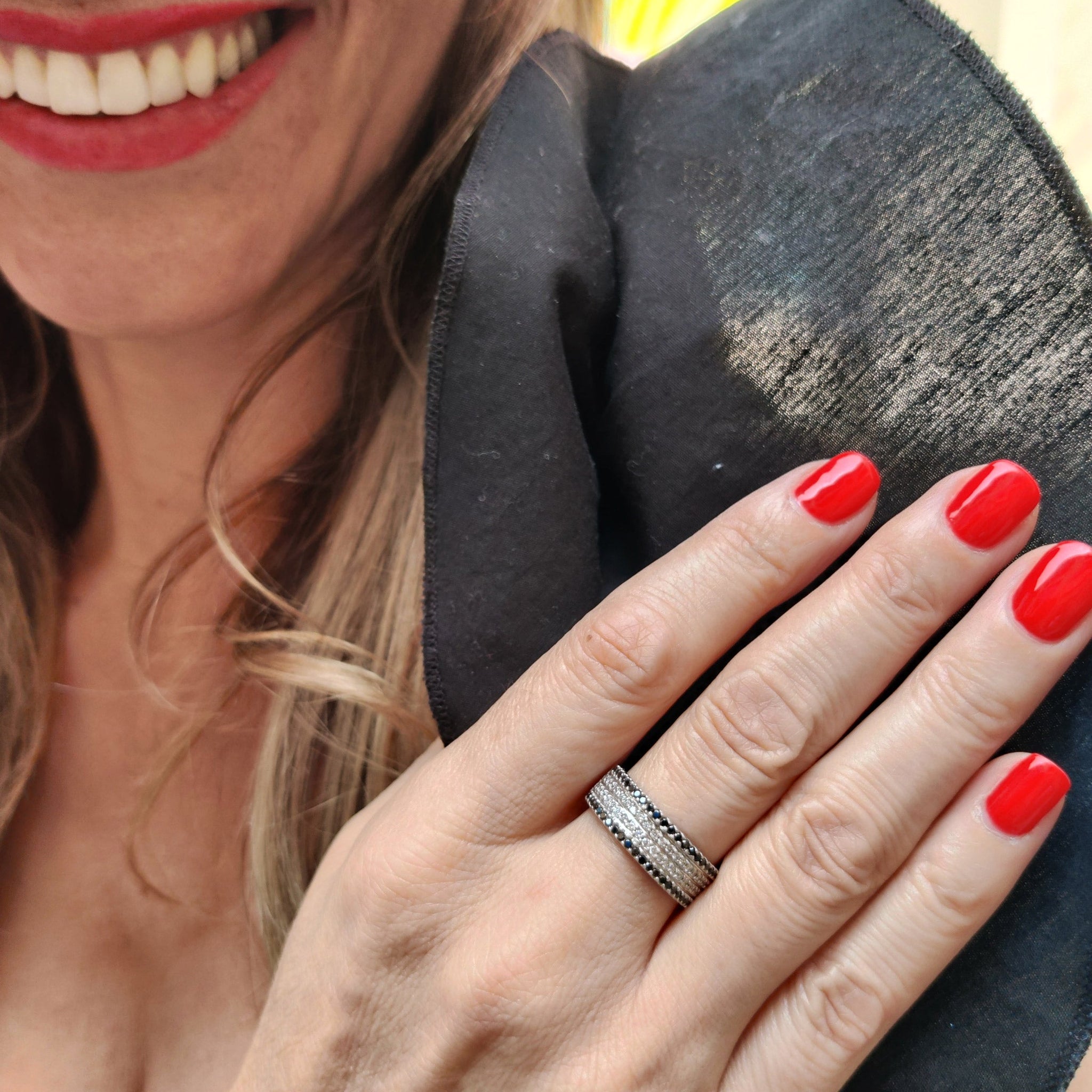 Woman showcasing a stunning black and white diamond ring on her finger with red nail polish.