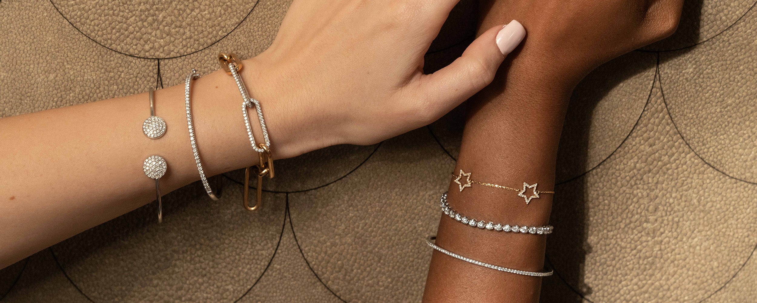 Elegant hands wearing diamond fine jewellery bracelets showcasing unique designs and exquisite craftsmanship.