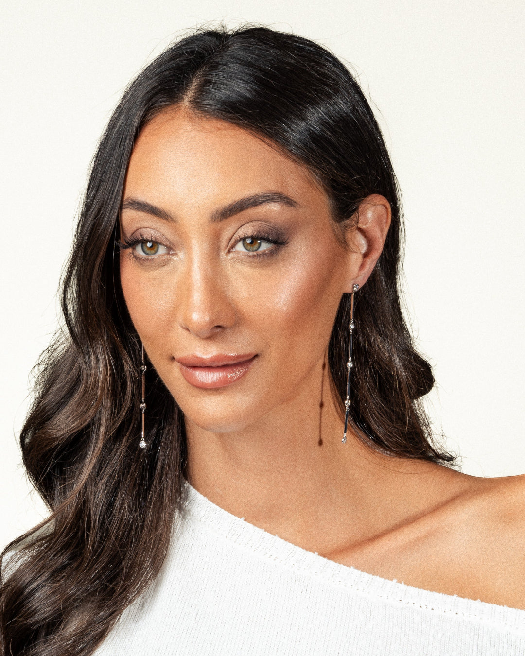 Elegant woman showcasing Cascade Diamond earrings in 18ct white gold, featuring a stunning cascading design.