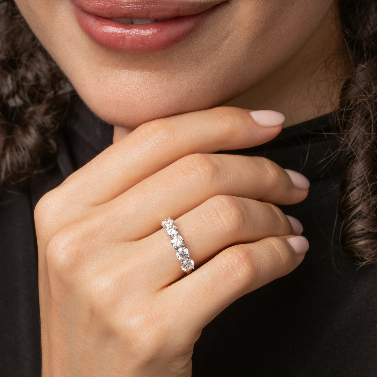 Model showcasing a classic five stone diamond ring, featuring brilliant cut diamonds set in a modern open basket setting.