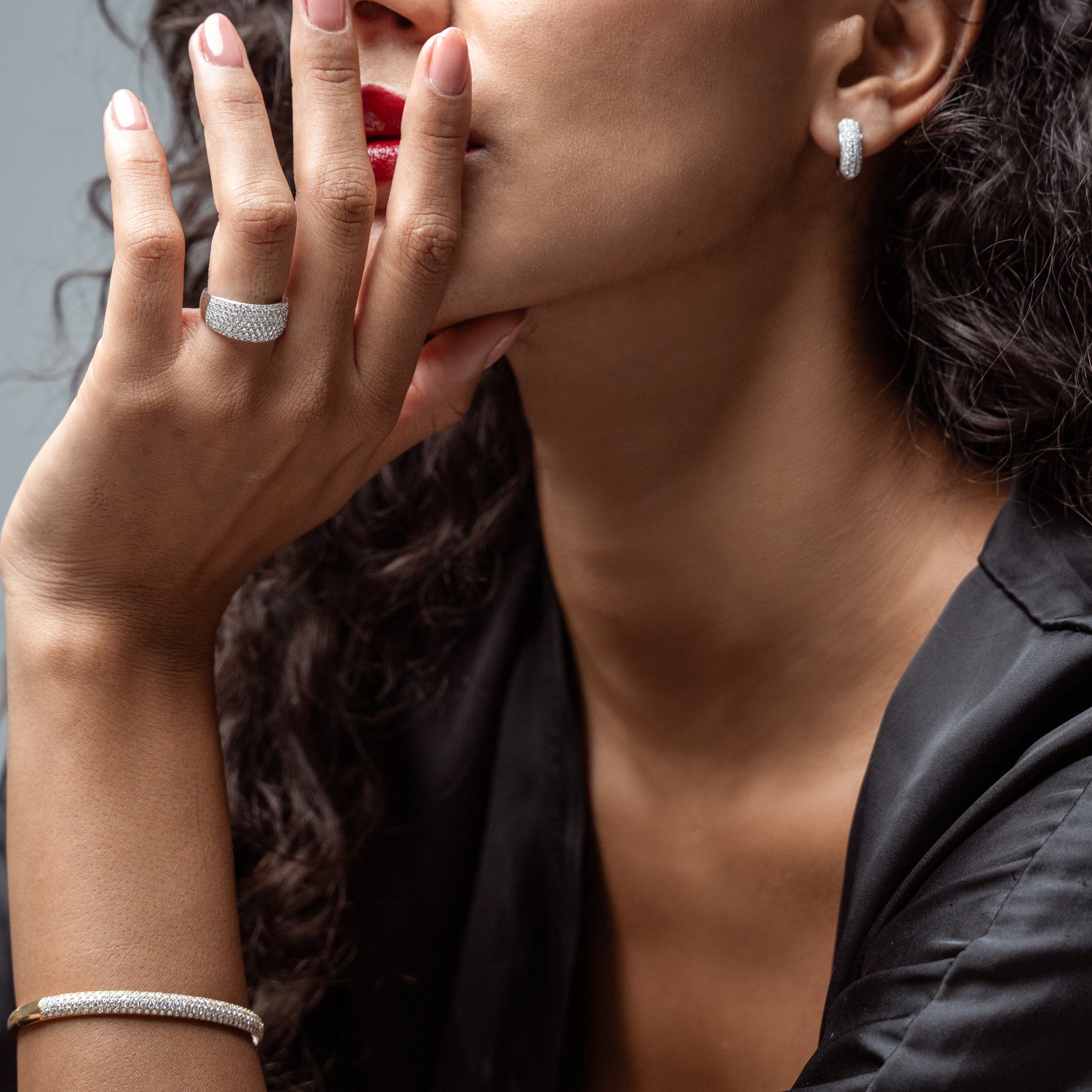 Close-up of a woman wearing diamond jewellery, including earrings, ring, and bracelet.