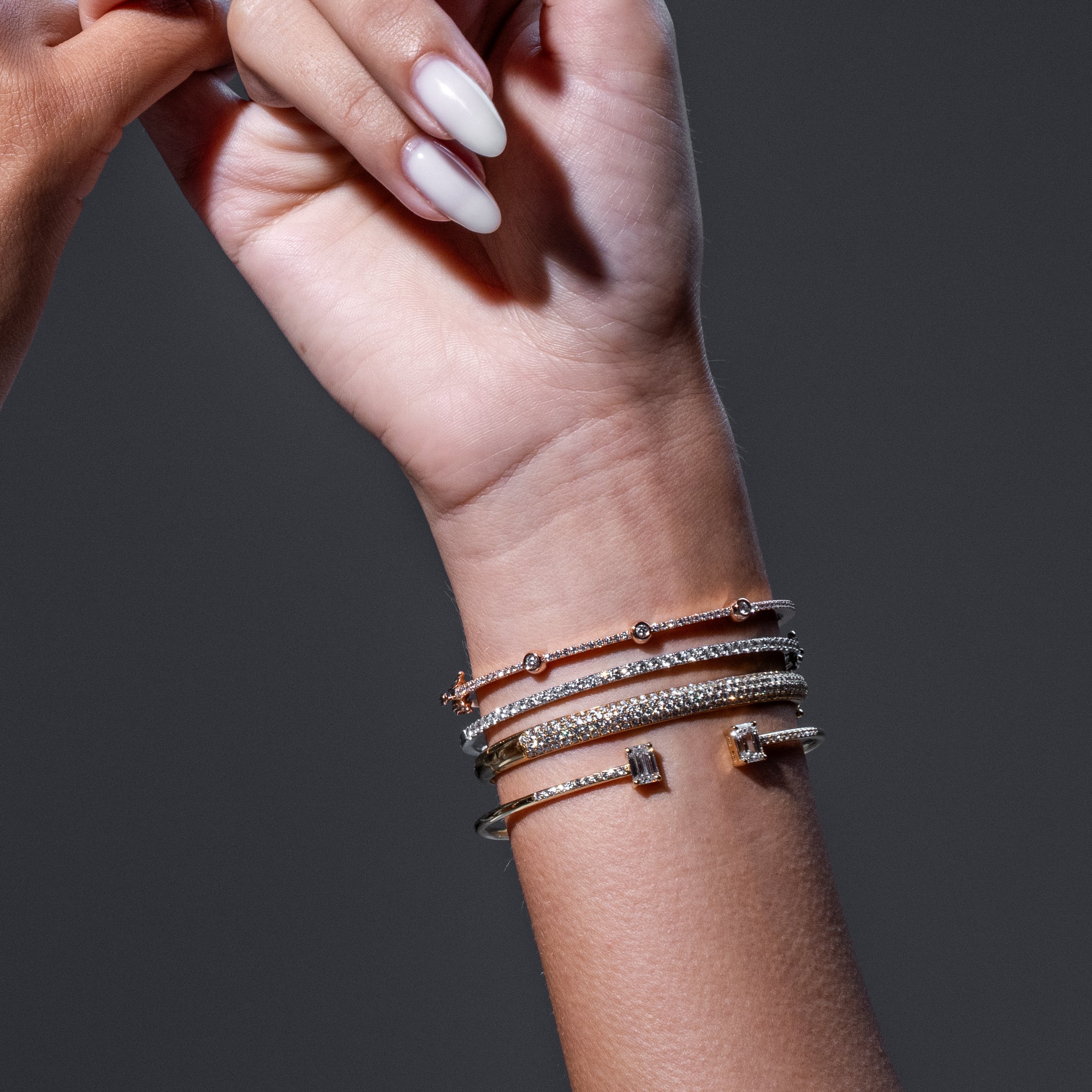 Close-up of a wrist wearing multiple diamond bracelets on a dark background