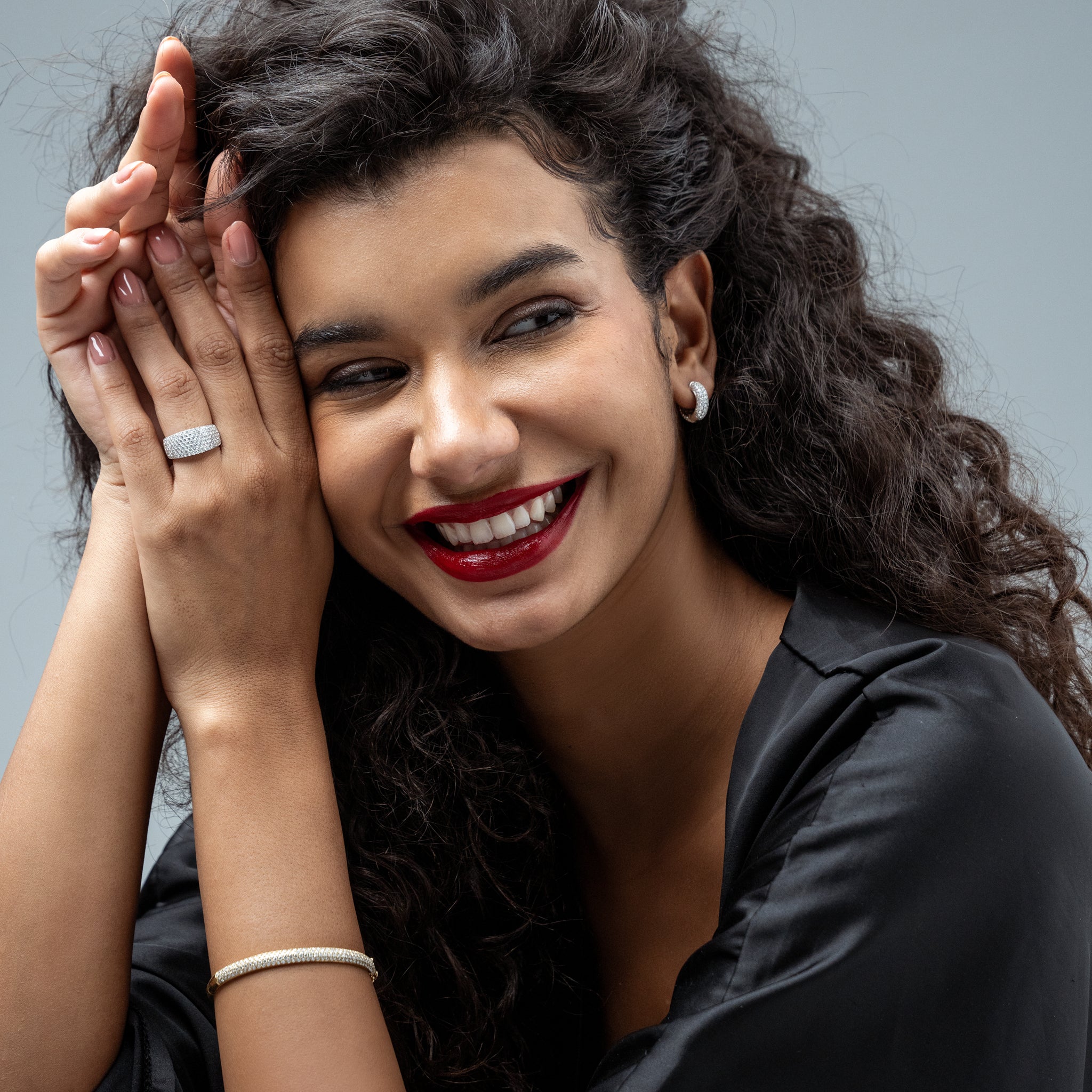 Woman with curly hair smiling wearing a diamond jewellery