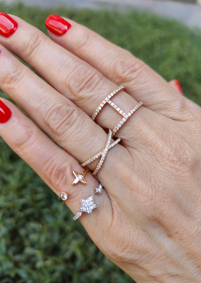 Hand adorned with multiple elegant diamond rings showcasing a star design and various styles in gold settings.