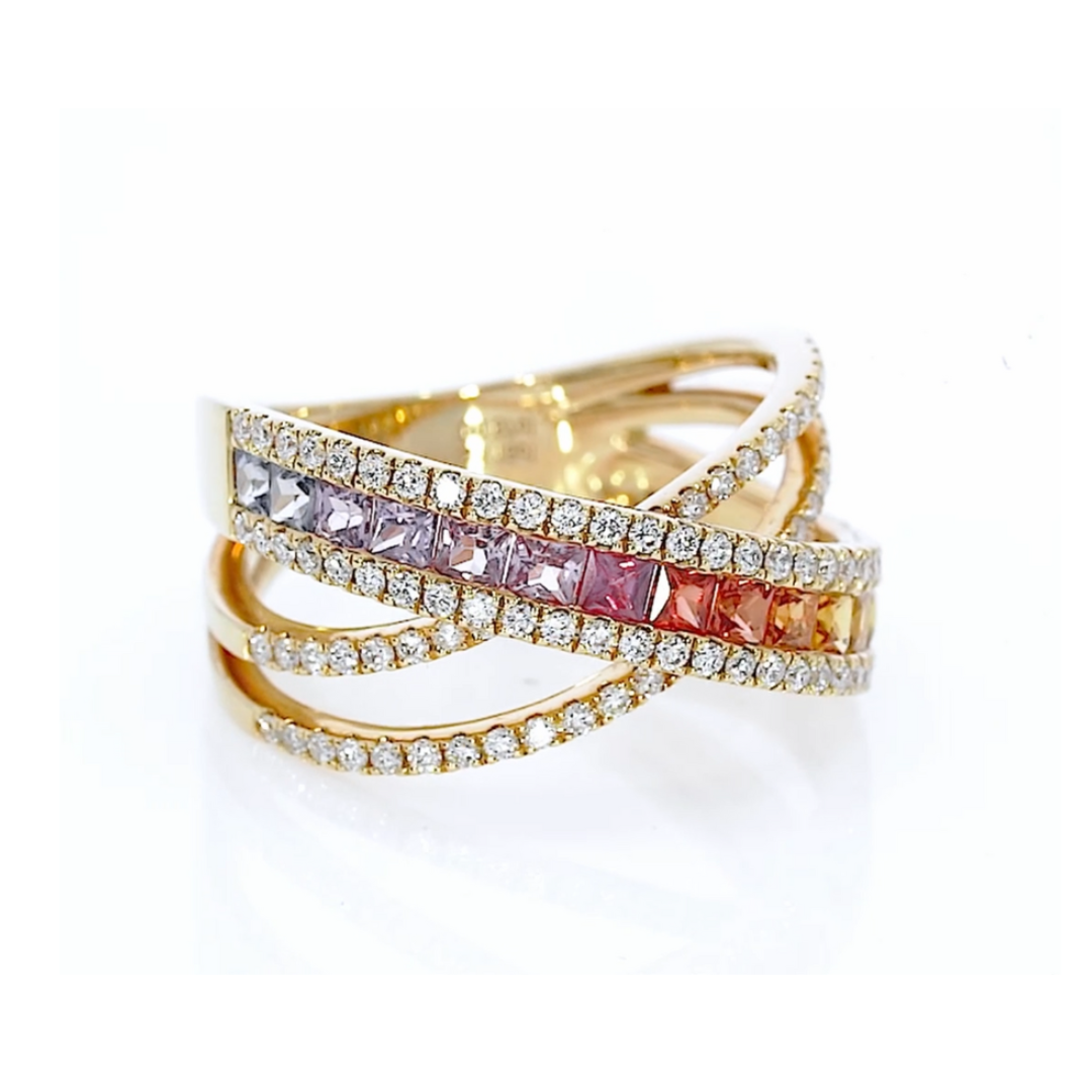 Criss cross ring featuring fifteen coloured sapphires in green to blue hues, and round brilliant diamonds, set in 18ct gold.