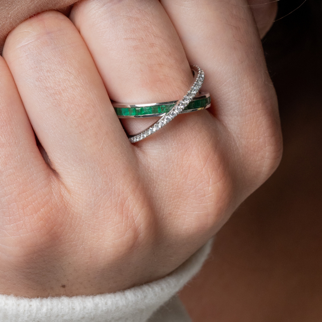 Close-up of an emerald criss cross ring featuring green emeralds and diamonds, a stunning gemstone ring design.