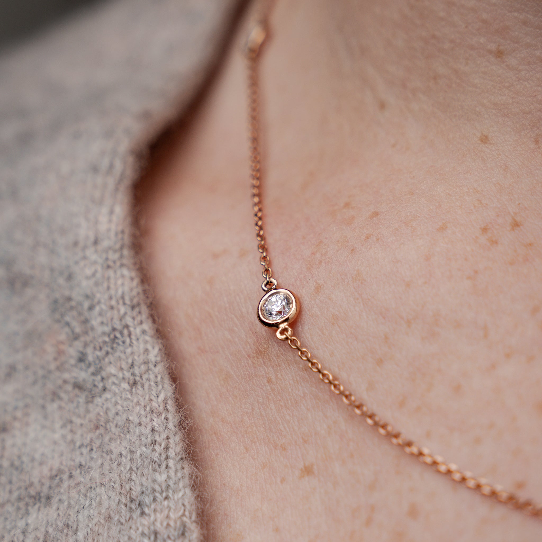 Constellation necklace featuring certified diamond on delicate rose gold chain worn on a cozy sweater.