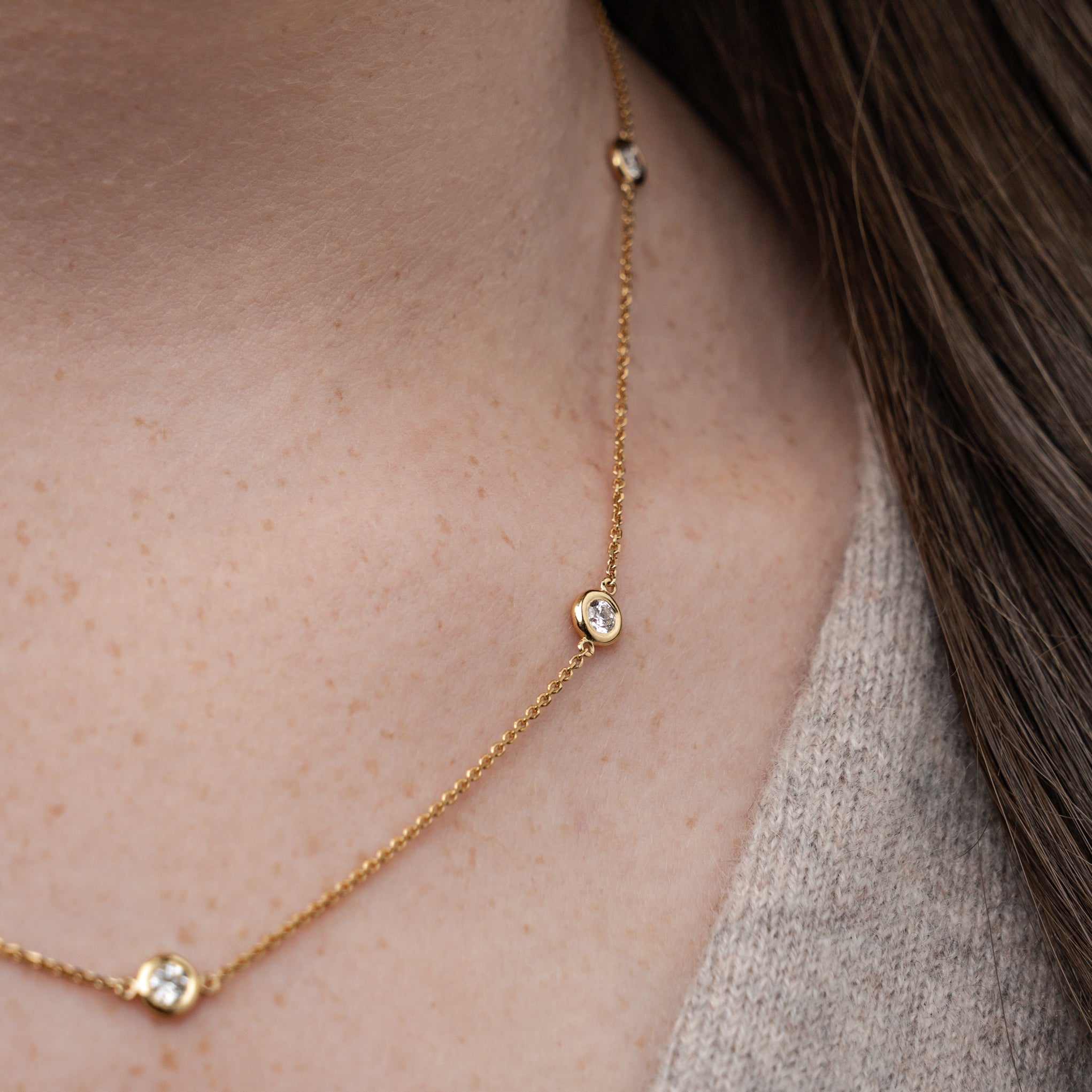 Close-up of a certified diamond necklace on a delicate gold chain, showcasing five brilliant cut diamonds.
