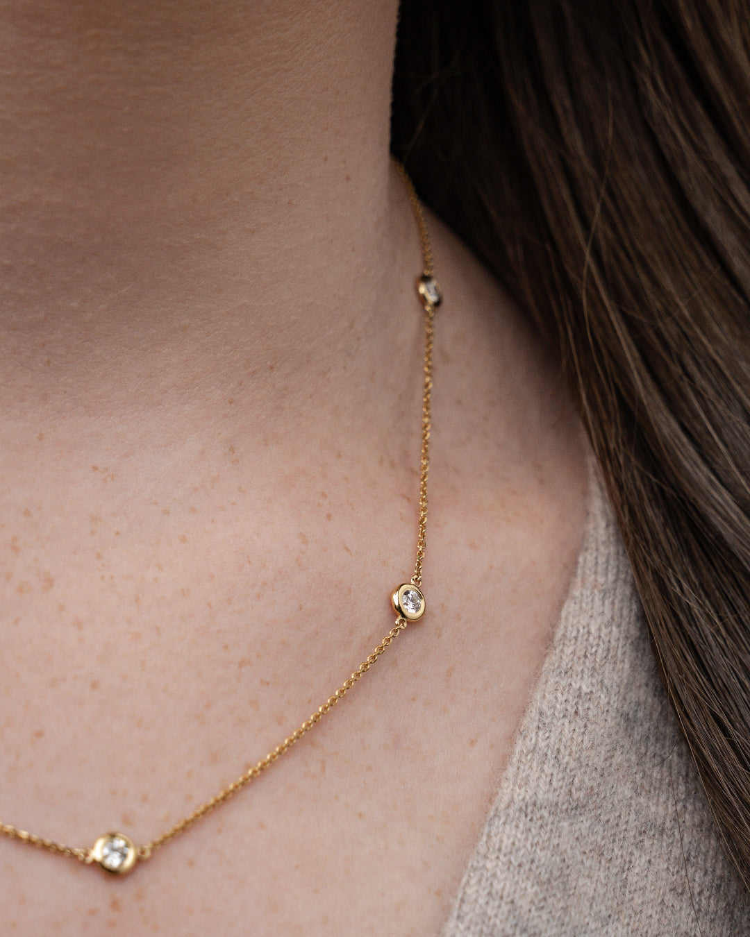 Close-up of a certified diamond necklace on a delicate gold chain, showcasing five brilliant cut diamonds.