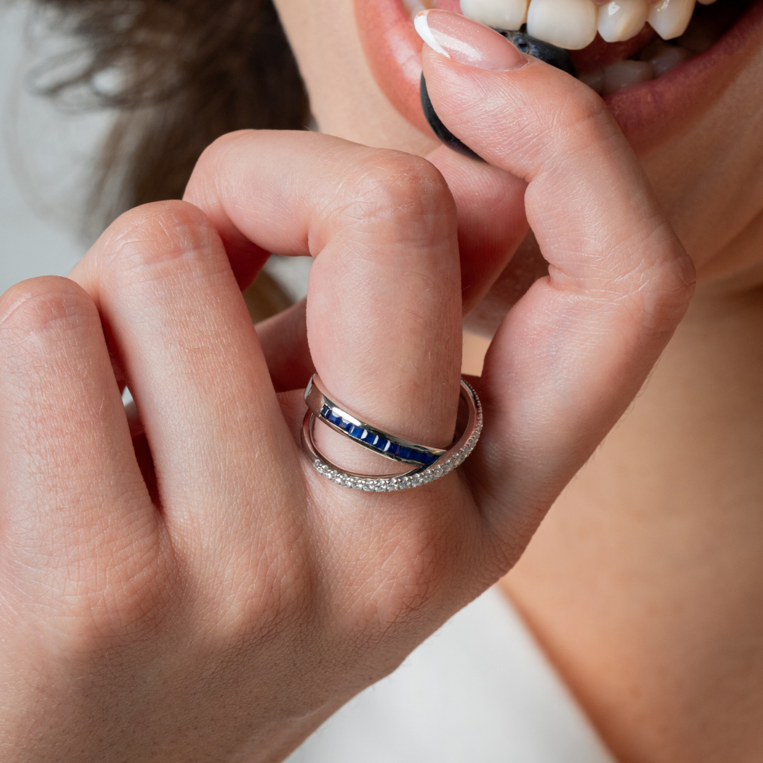Close-up of a hand showcasing a sapphire criss cross ring with brilliant cut diamonds, highlighting the beautiful gemstone ring.