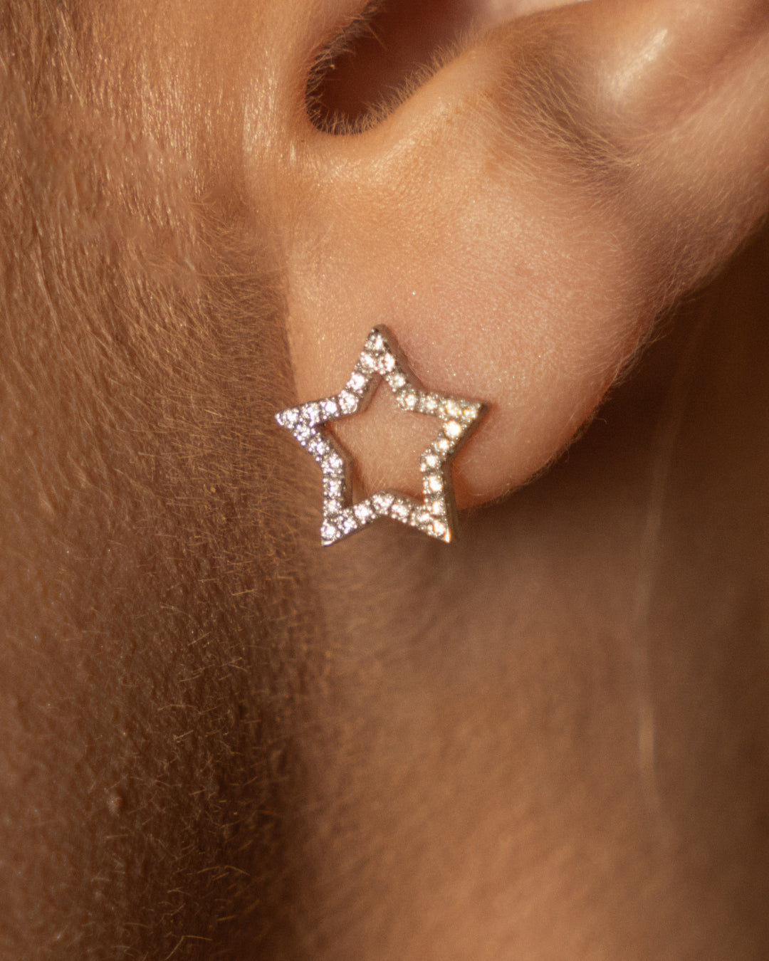 Close up of certified diamond earrings shaped like stars, set in 18ct gold, worn on earlobe.