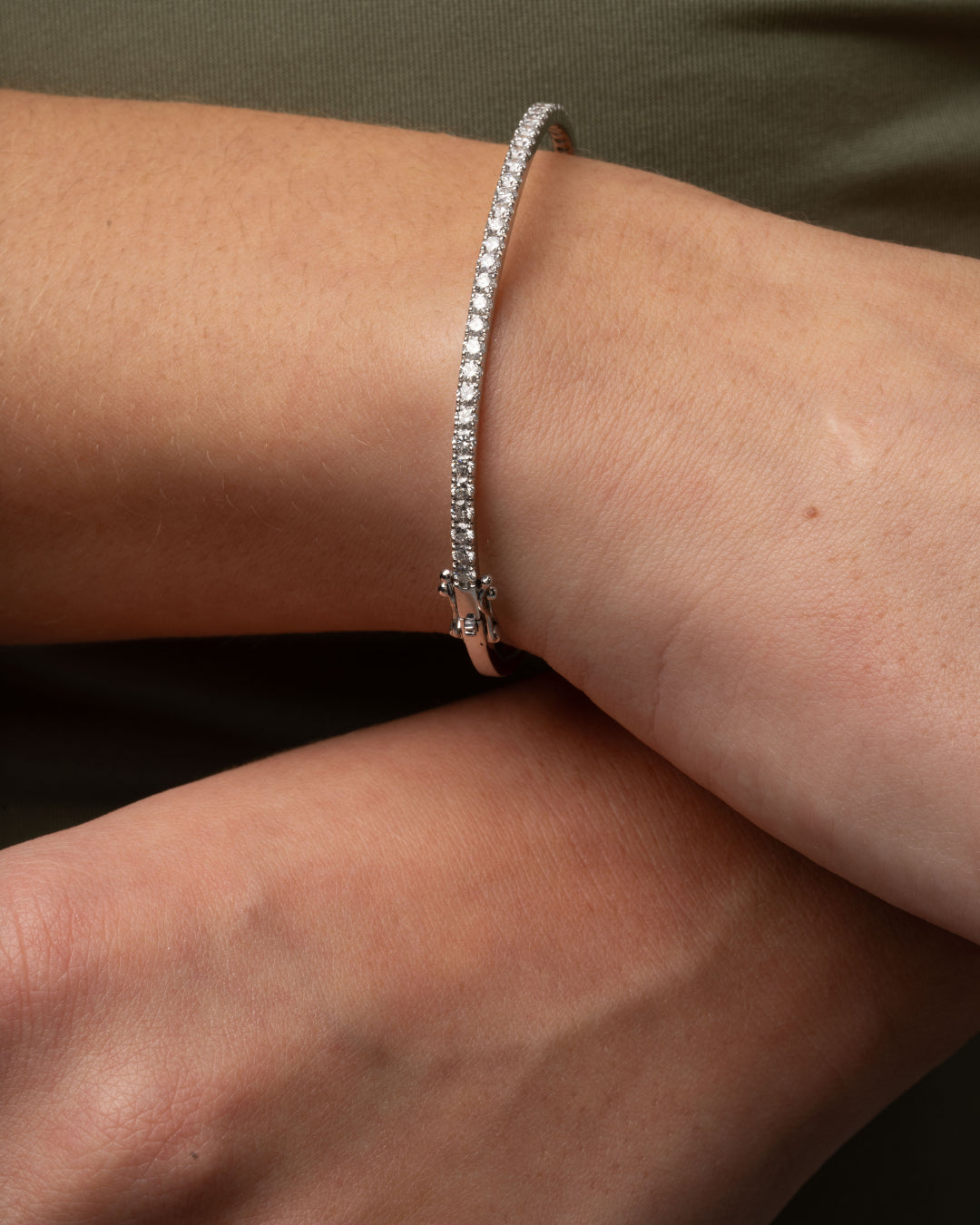 Close-up of a diamond tennis bangle on a wrist showcasing diamonds in solid gold.