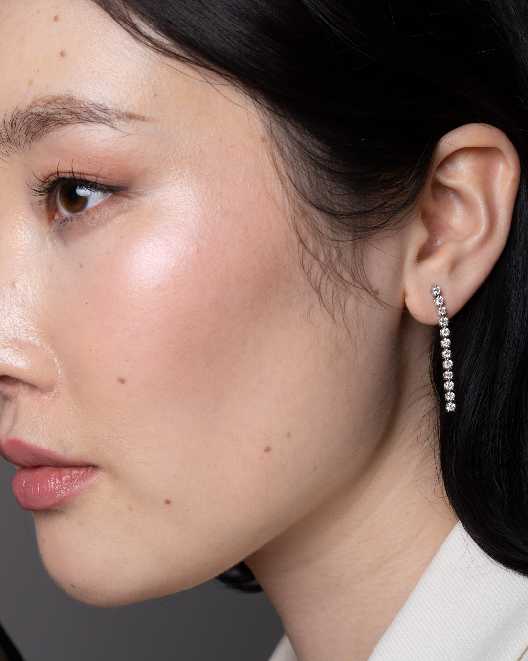 Side profile of a woman wearing diamond earrings with cascading diamonds, showcasing timeless glamour.