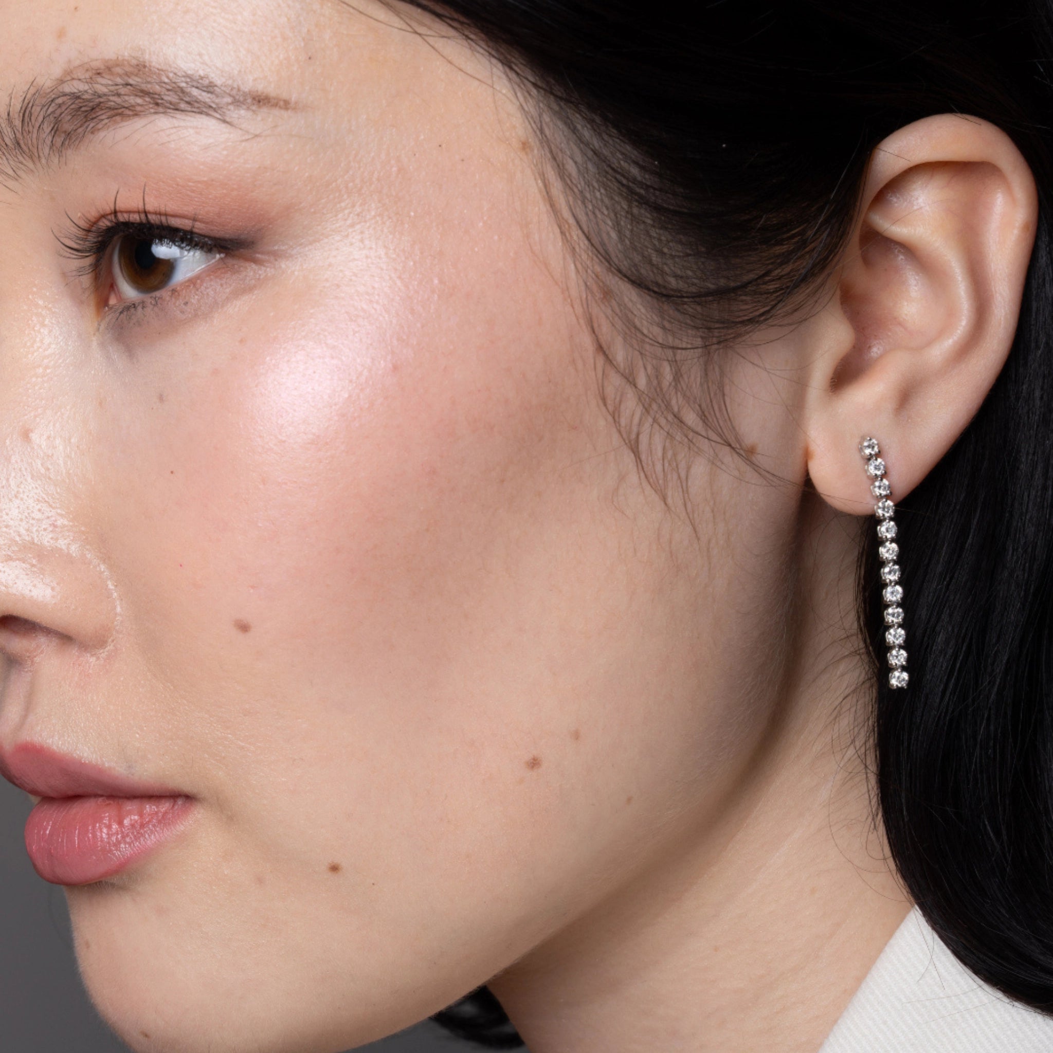 Side profile of a woman wearing diamond earrings with cascading diamonds, showcasing timeless glamour.