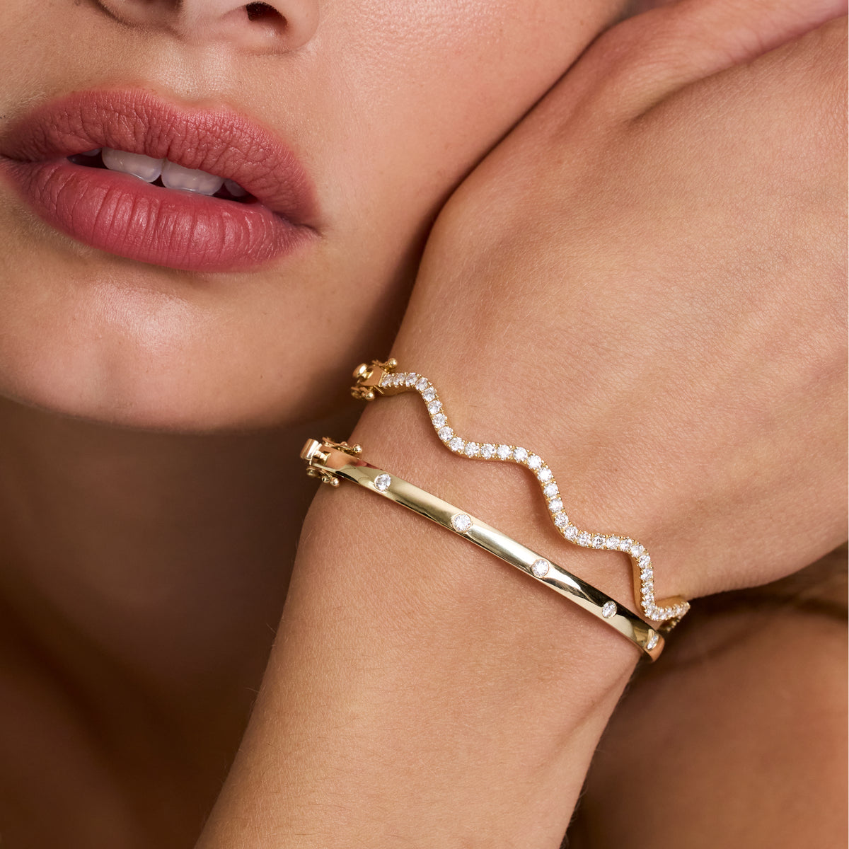 Elegant Diamond Wave Bangle in gold worn on a wrist, showcasing its sparkling diamonds and unique wavy design.