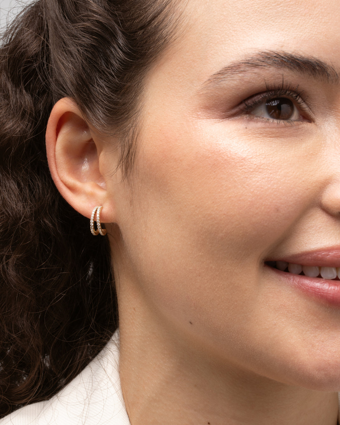 Close up of model wearing double row diamond huggies showcasing certified diamond earrings in 18ct gold.