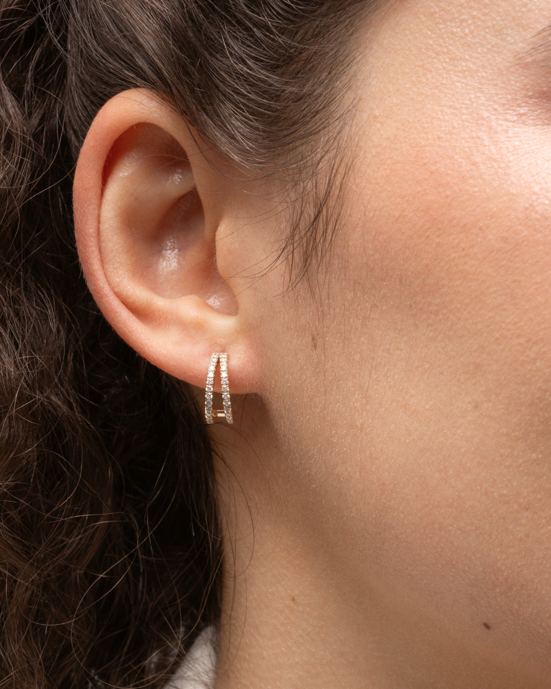 Close-up of a woman wearing elegant double row diamond huggies crafted with  certified diamond earrings set in 18ct gold.