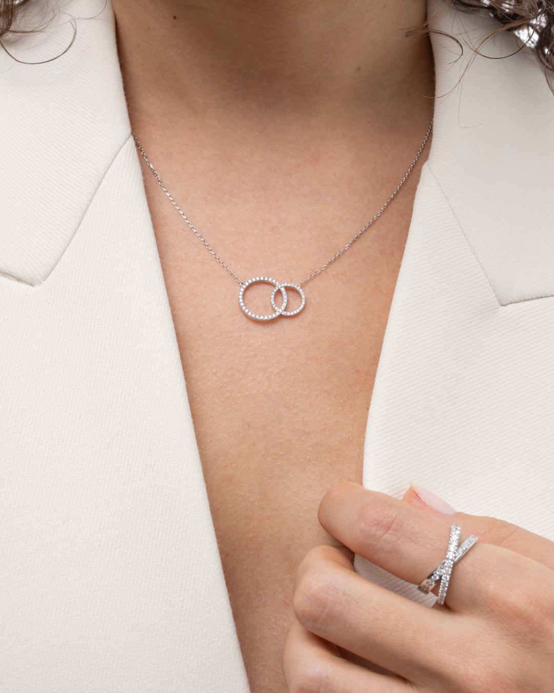 Close-up of a woman wearing a certified diamond necklace featuring two interlocking circles, accentuating elegance.