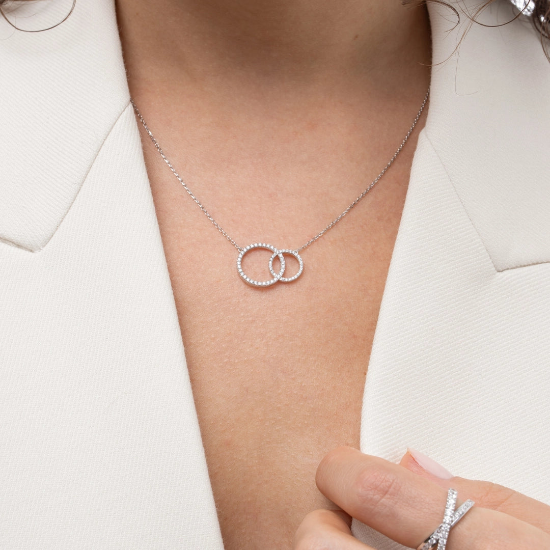 Close-up of a woman wearing a certified diamond necklace featuring two interlocking circles, accentuating elegance.