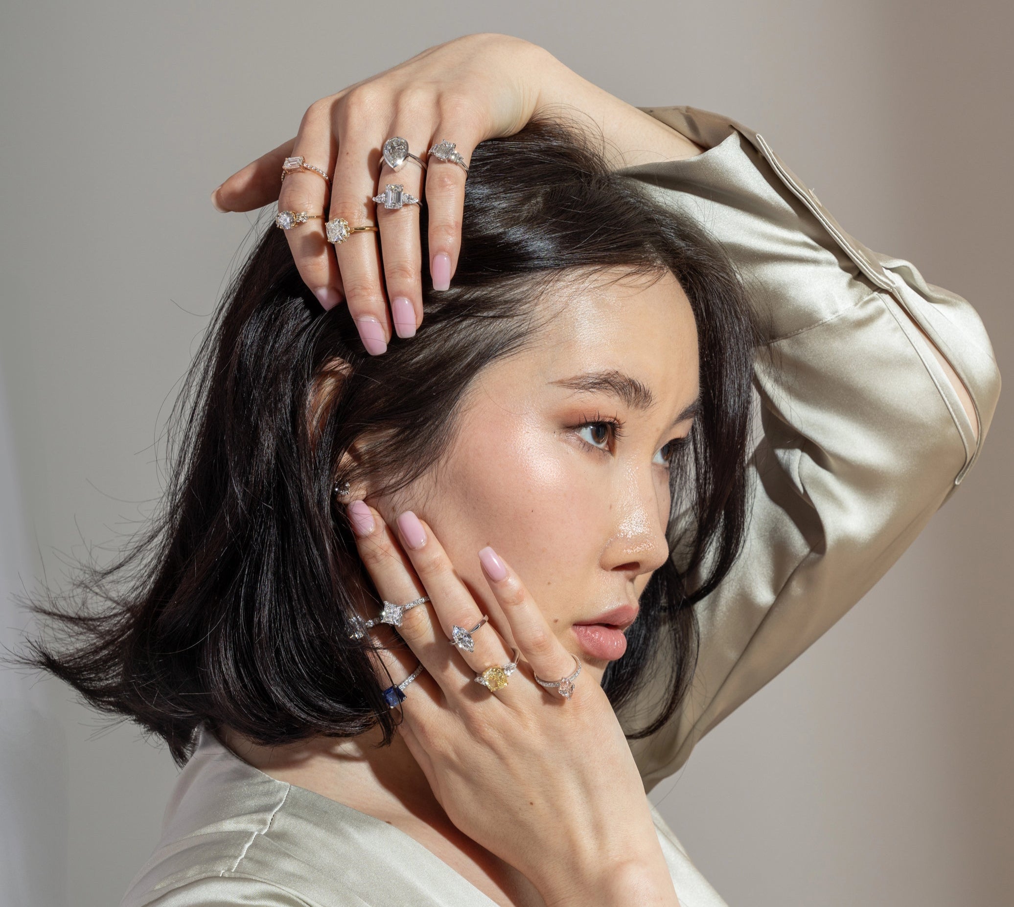 Woman wearing multiple rings on a neutral background