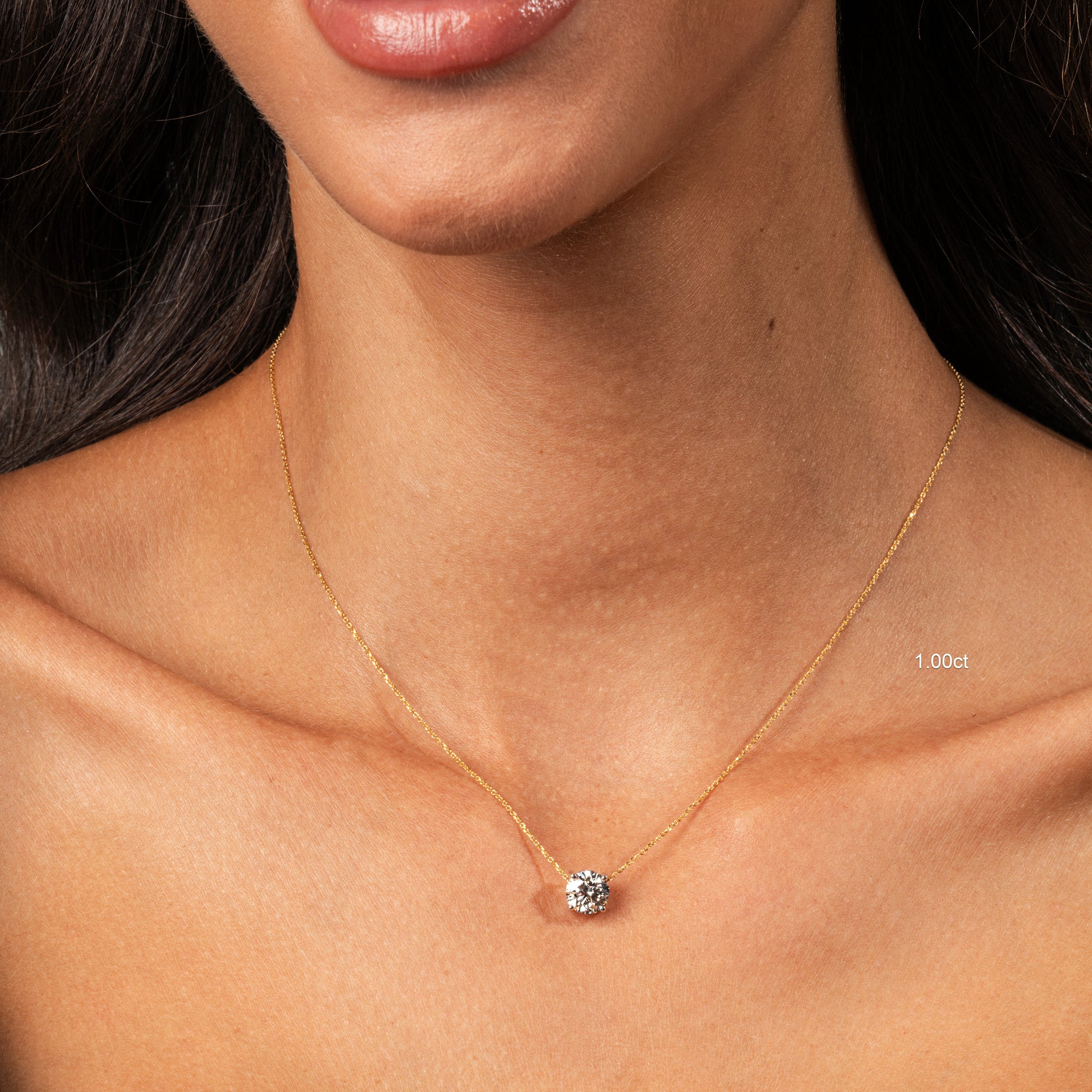 The Floating Diamond Necklace elegantly showcased on a model's neck, featuring a brilliant cut diamond on a gold chain.