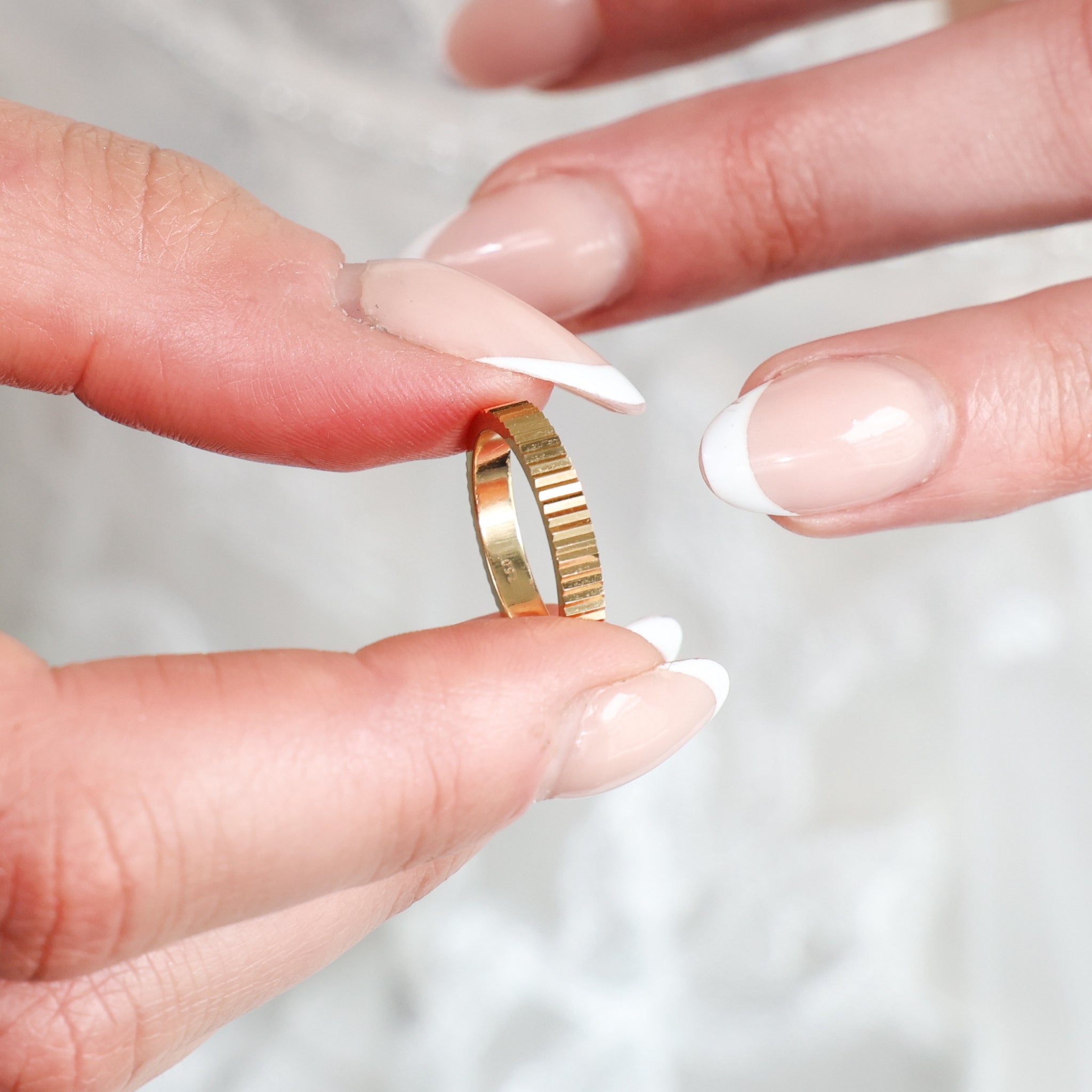 Fluted Wedding Band held between elegant fingers, showcasing its refined fluted texture and modern aesthetic.