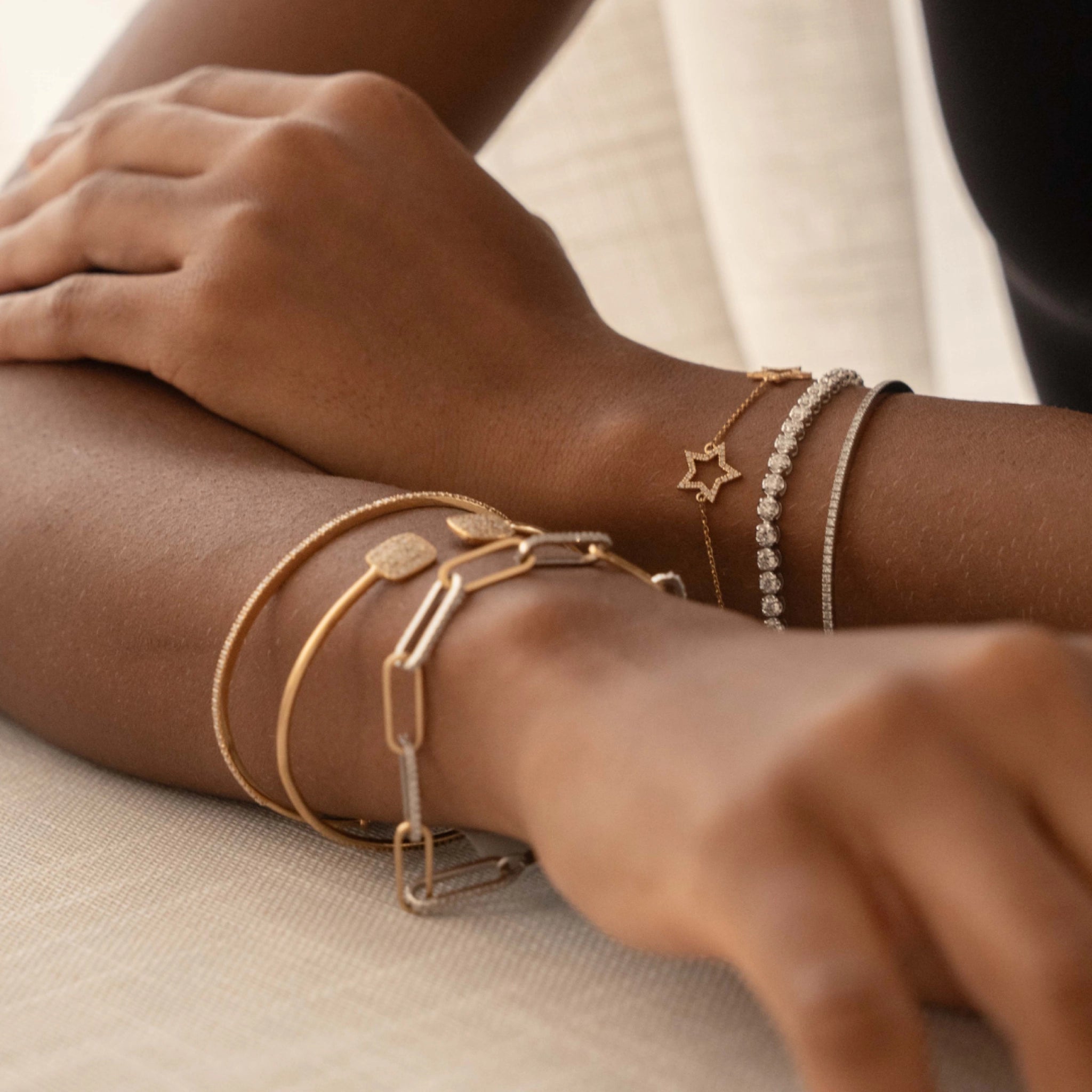 Close-up of a wrist with mixed gold and diamond bangles, showcasing a stylish diamond bangle and diamond bracelet.