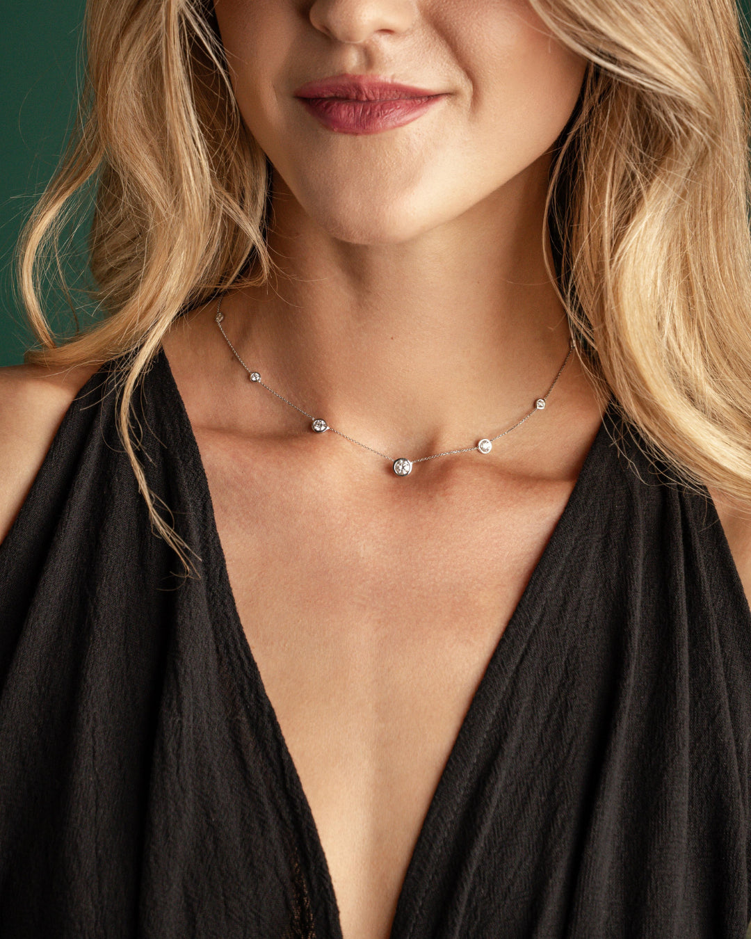 Woman wearing a graduating bezel settings diamond necklace with round brilliant cut diamonds