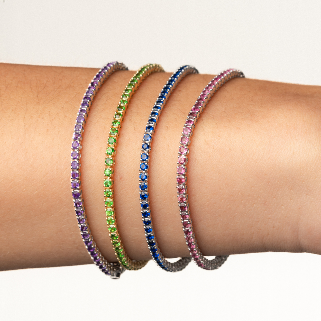Colourful gemstone tennis bracelets displayed on a wrist showcasing elegance and luxury.
