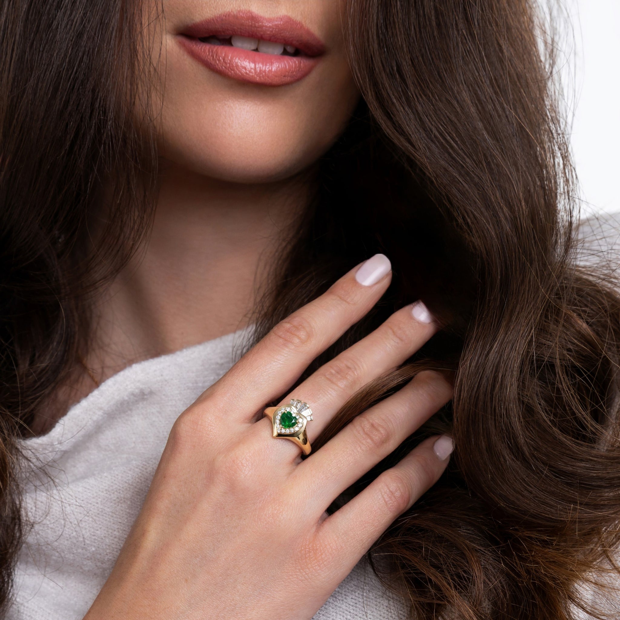Close-up of a woman wearing an elegant Claddagh ring featuring a green tsavourite , symbolizing Irish heritage.