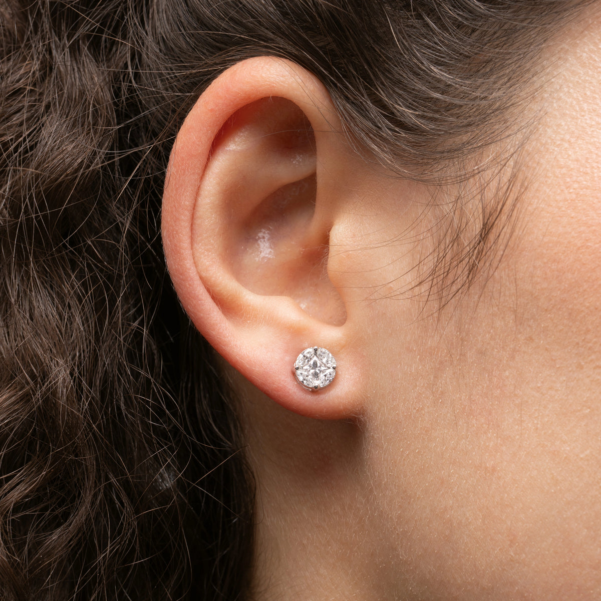 Close-up of a model wearing illusion stud earrings with certified diamonds in 18ct gold.