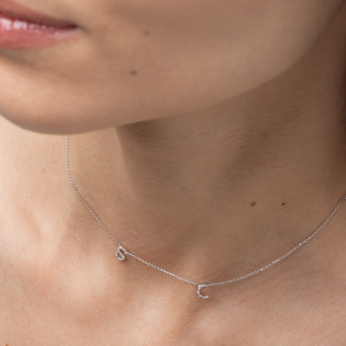 Love Letter necklace featuring certified diamond initials on a fine link chain, worn elegantly.