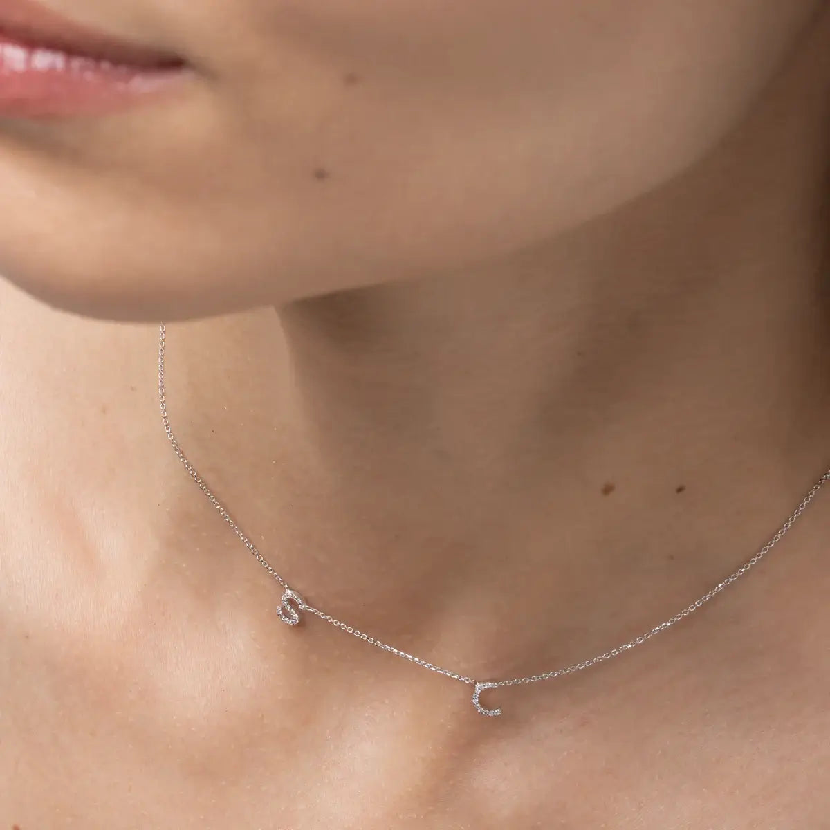Love Letter necklace featuring certified diamond initials on a fine link chain, worn elegantly.