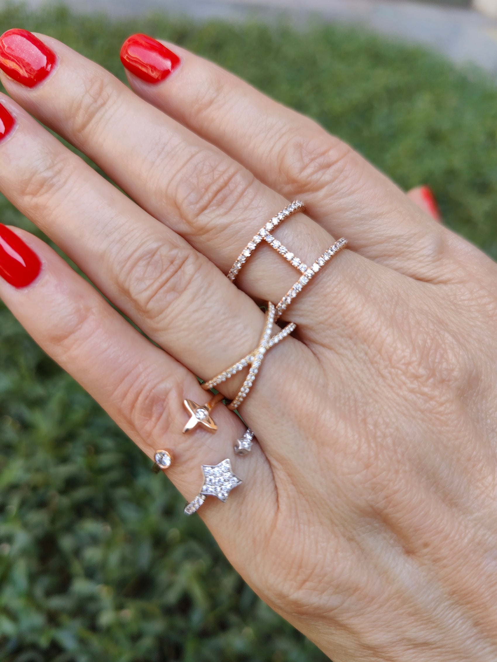 Hand adorned with multiple rings, including a diamond star ring and sparkling designs on beautifully manicured nails.