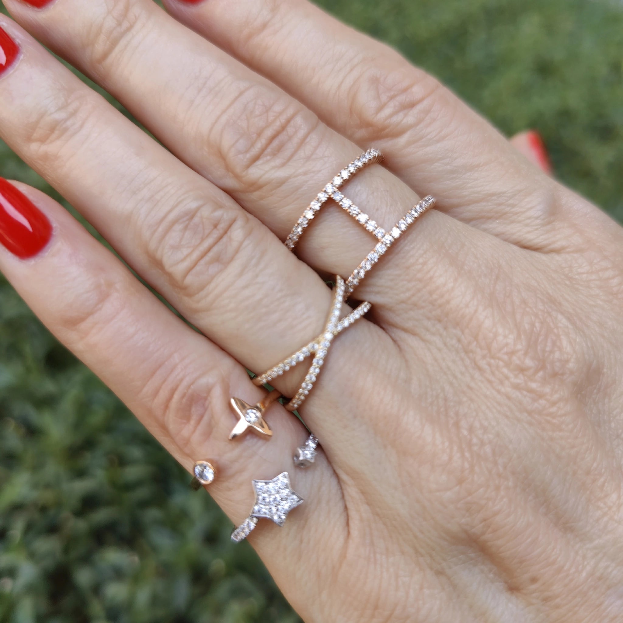 Hand adorned with multiple rings, including a diamond star ring and sparkling designs on beautifully manicured nails.