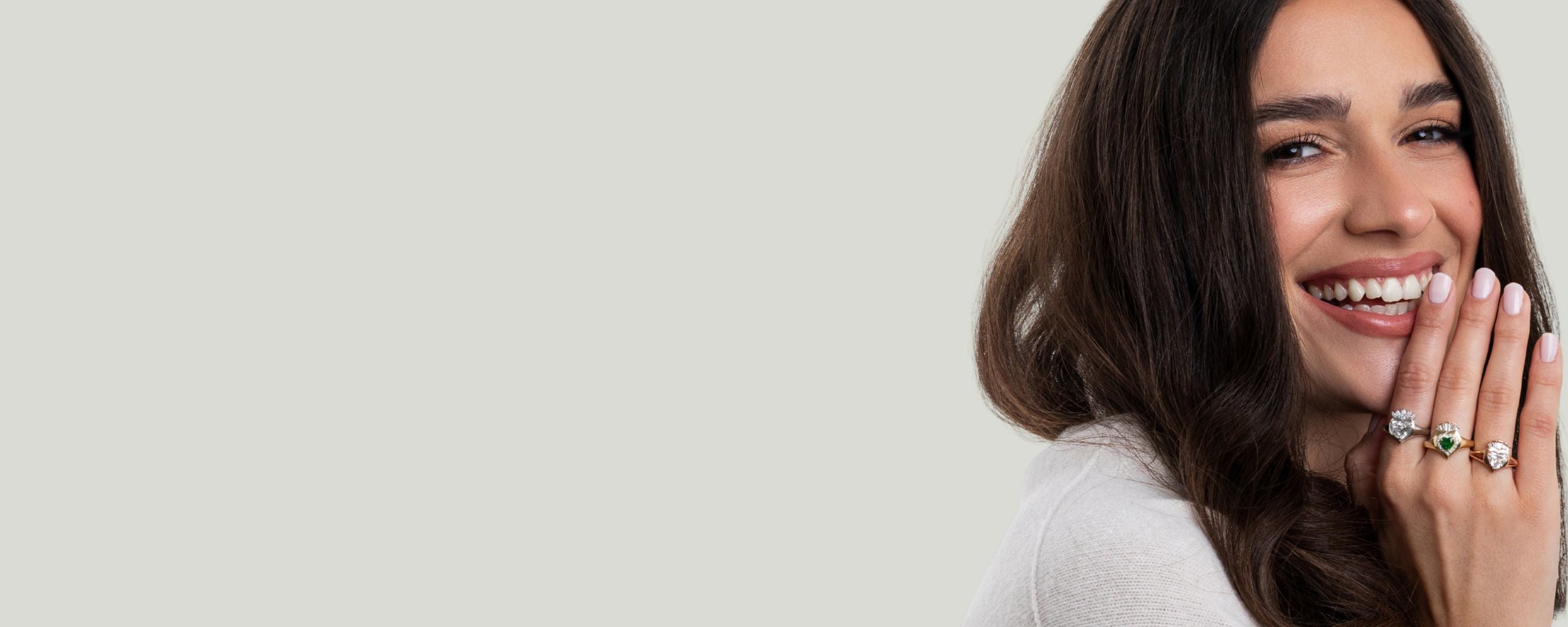 Woman wearing claddagh rings on a light gray background